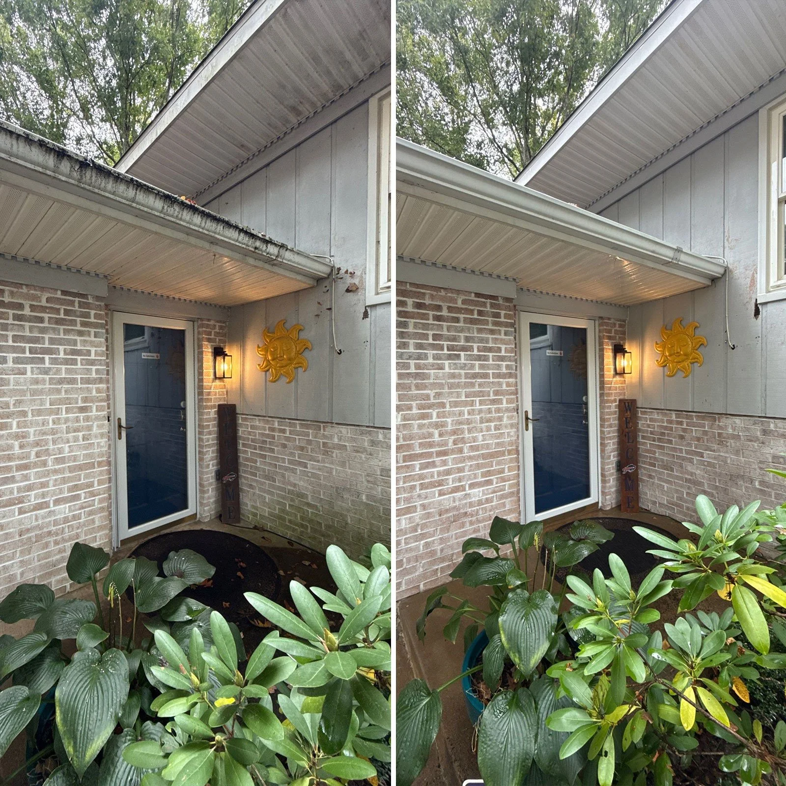 Side view of a house corner with brick and light gray exterior, decorative yellow sun wall art, and green plants in pots at the front. The house features a white door with a glass panel, a wall-mounted light, and a 