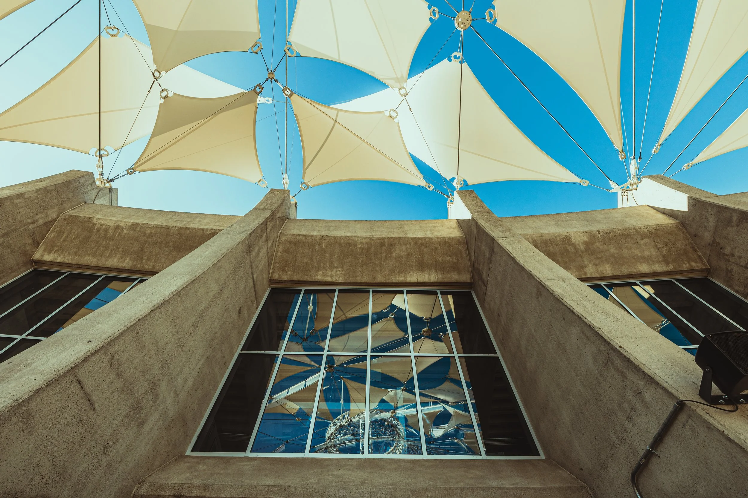 Looking up at the building's window with the sky and decorative umbrellas reflected in the glass.