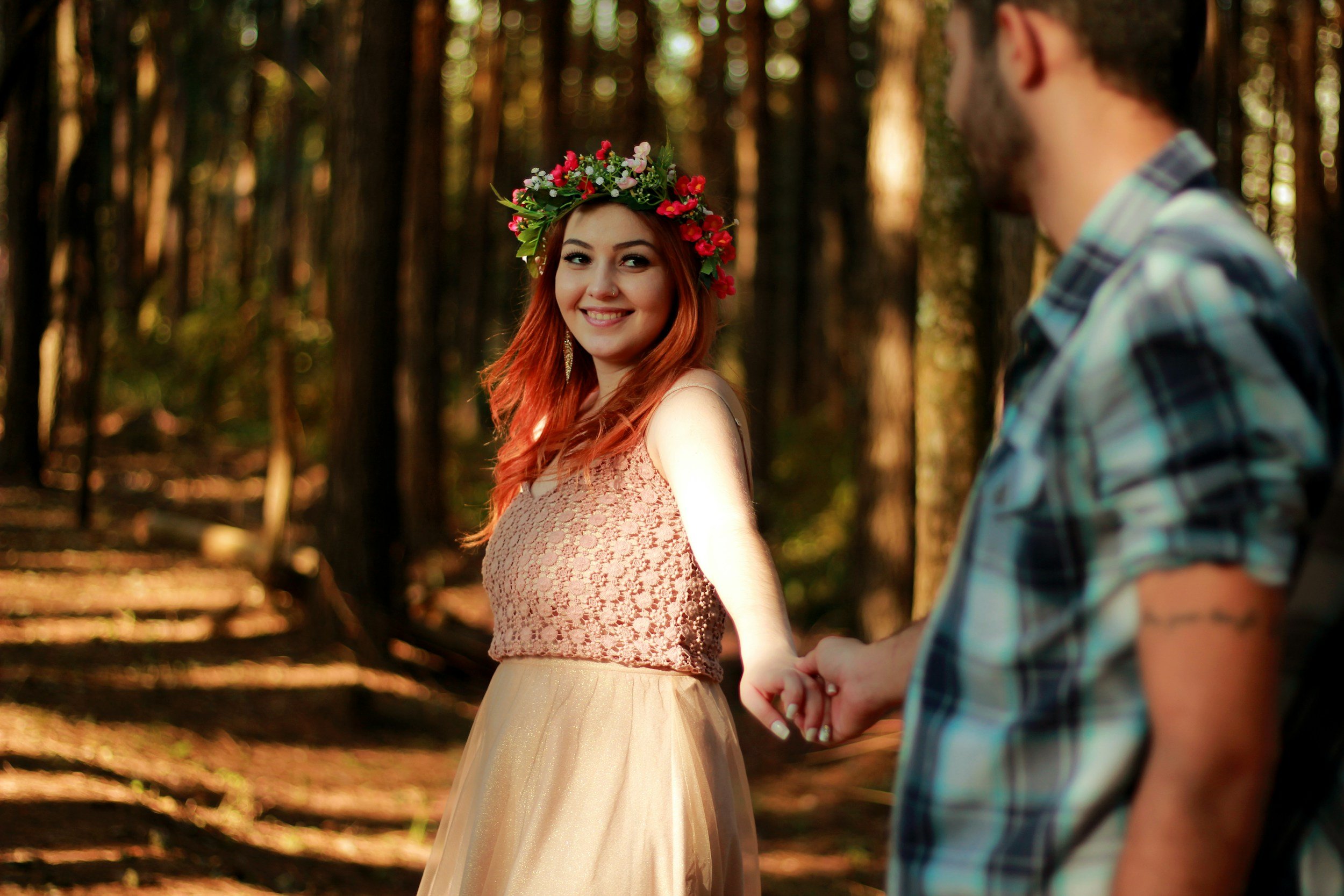 Woman with red hair and flower crown smiling and holding a man's hand resembling Therapy for Individuals