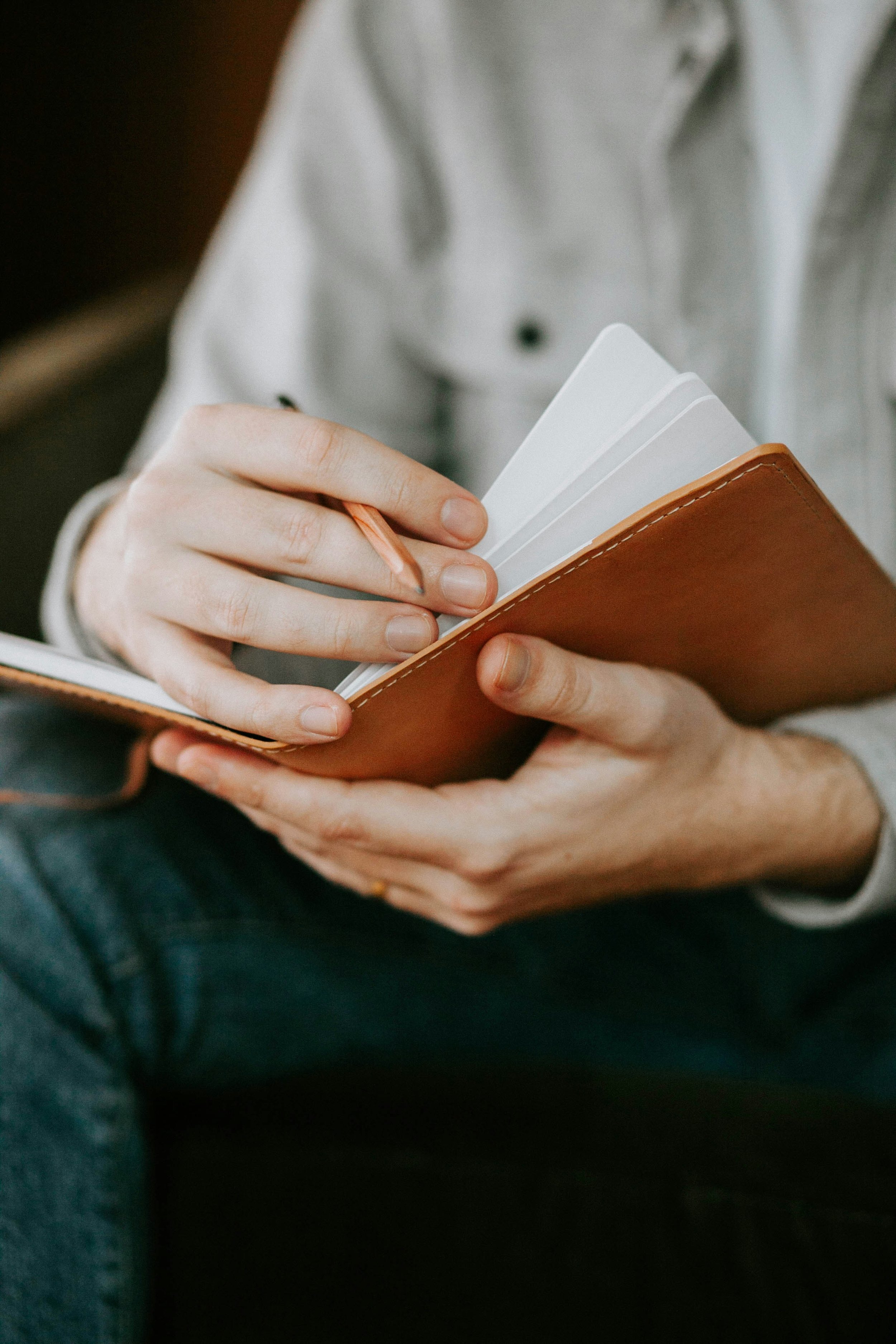 Man's hands holding a pencil and a leather notebook