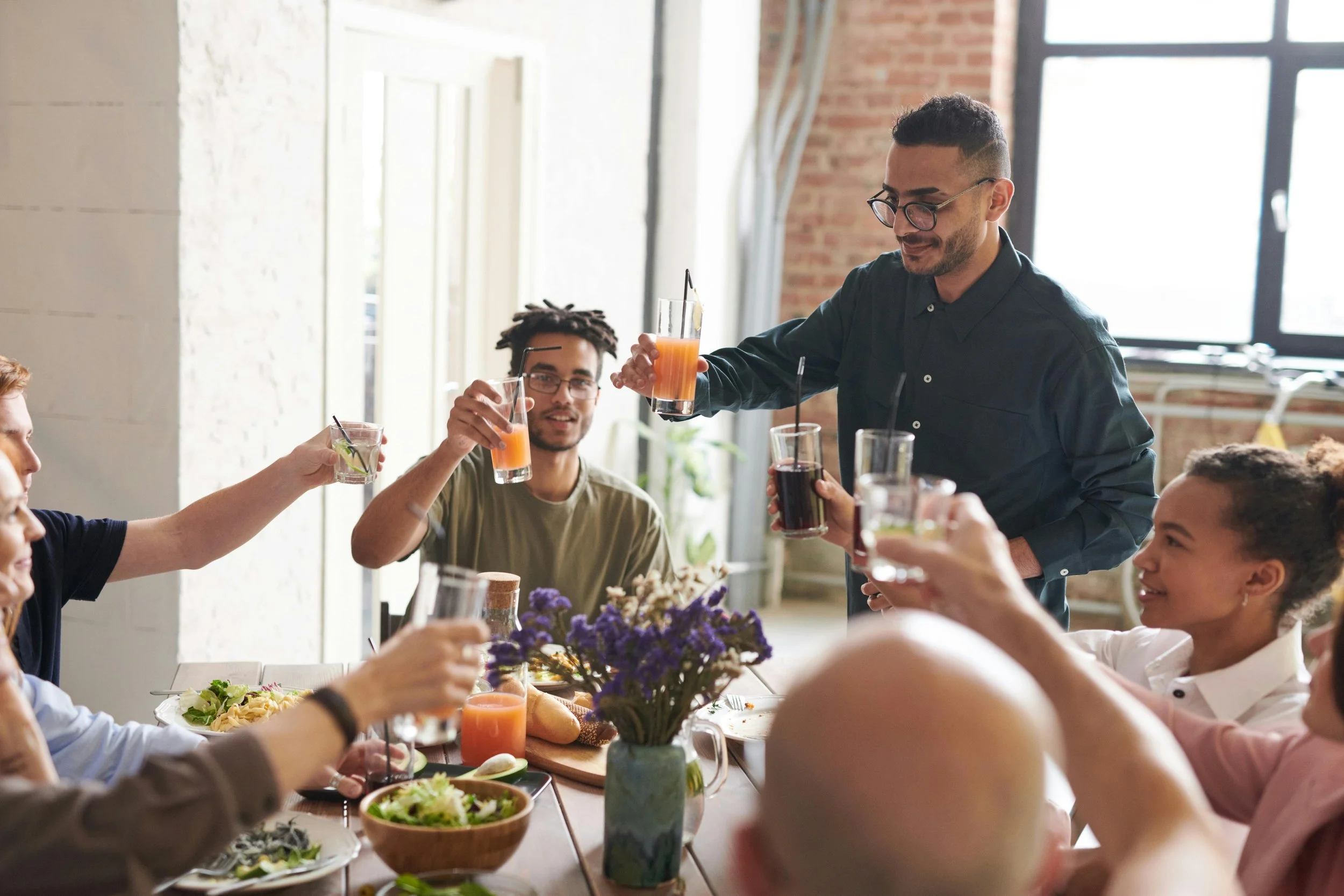 Two men with glasses at a table raising glasses for a toast to therapy for individuals