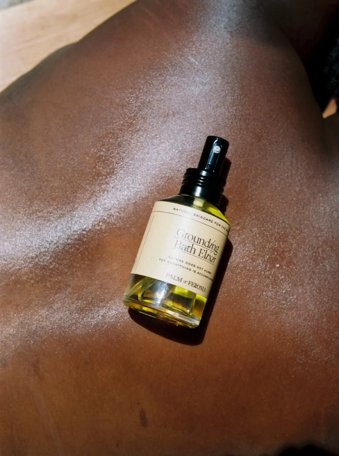 Grounding Bath Elixir by Palm of Feronia resting on bare skin.