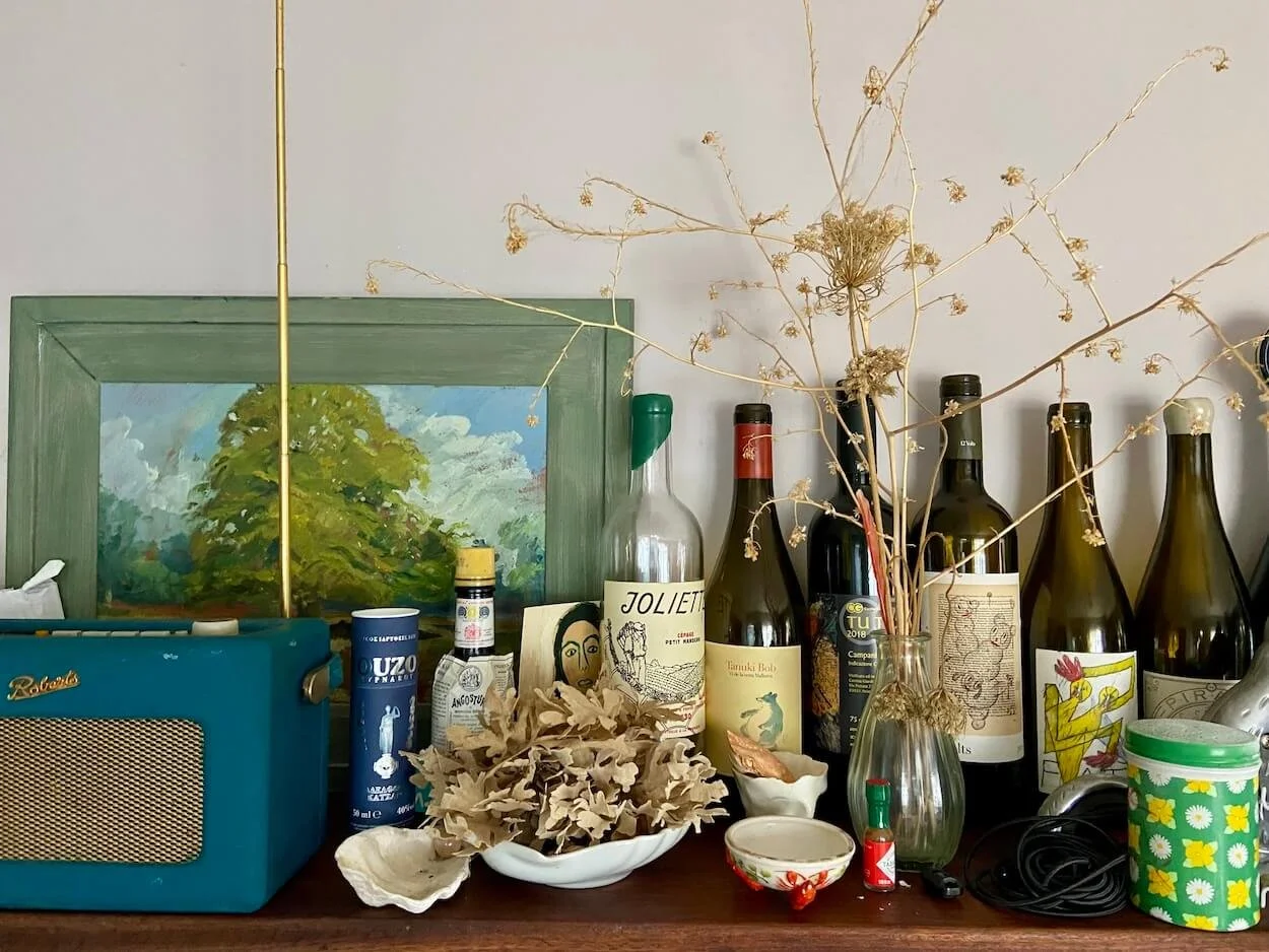 Shelf detail in Alexandra Mann's home featuring dried flowers, seaweed, paintings, a radio and collected objects.