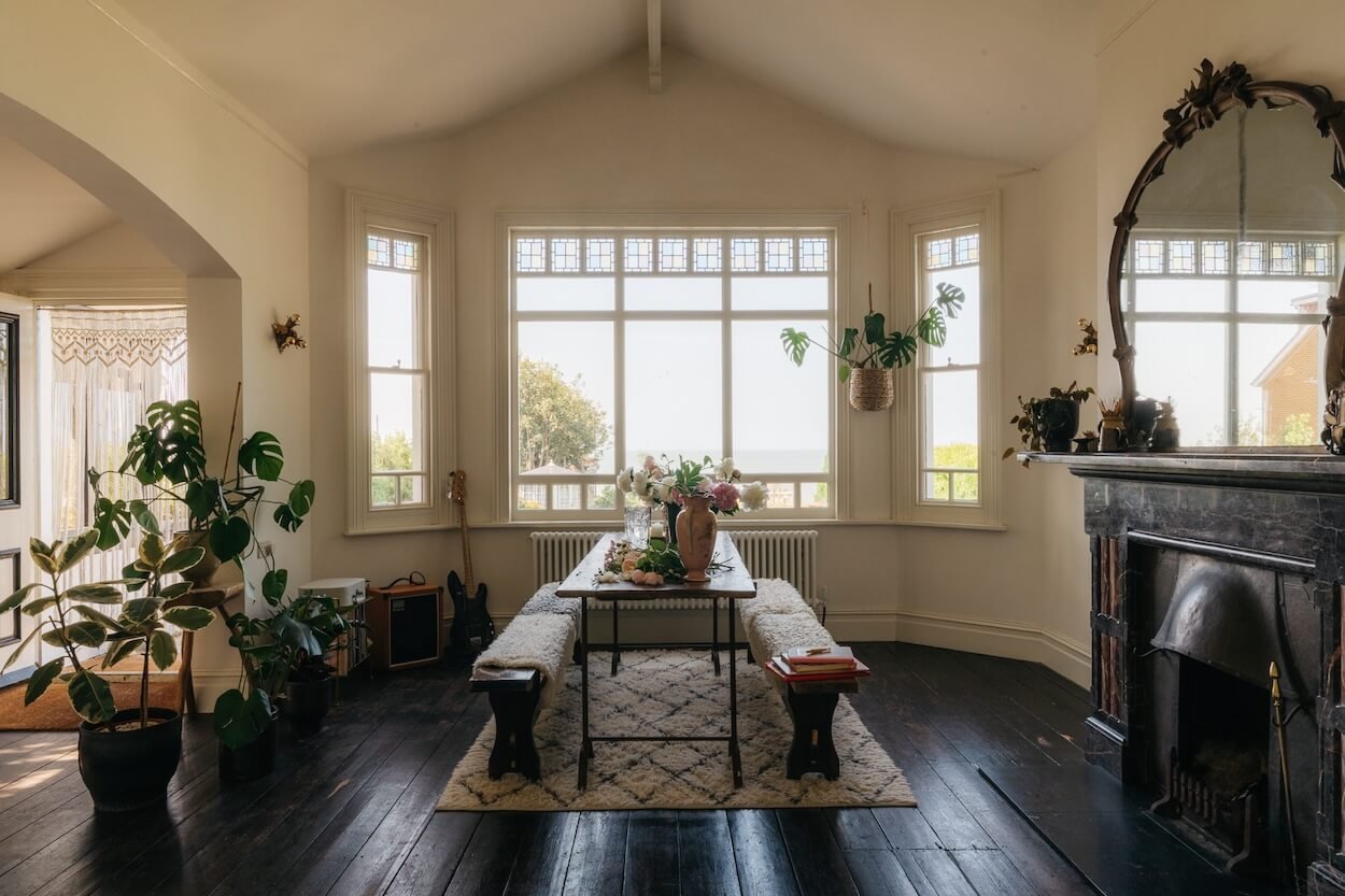 Drawing room at Sea Tower during a working day, with vases and loose flowers on the table capturing the atmosphere of preparation for a shoot styled by Emily Chalmers for Caravan Style.