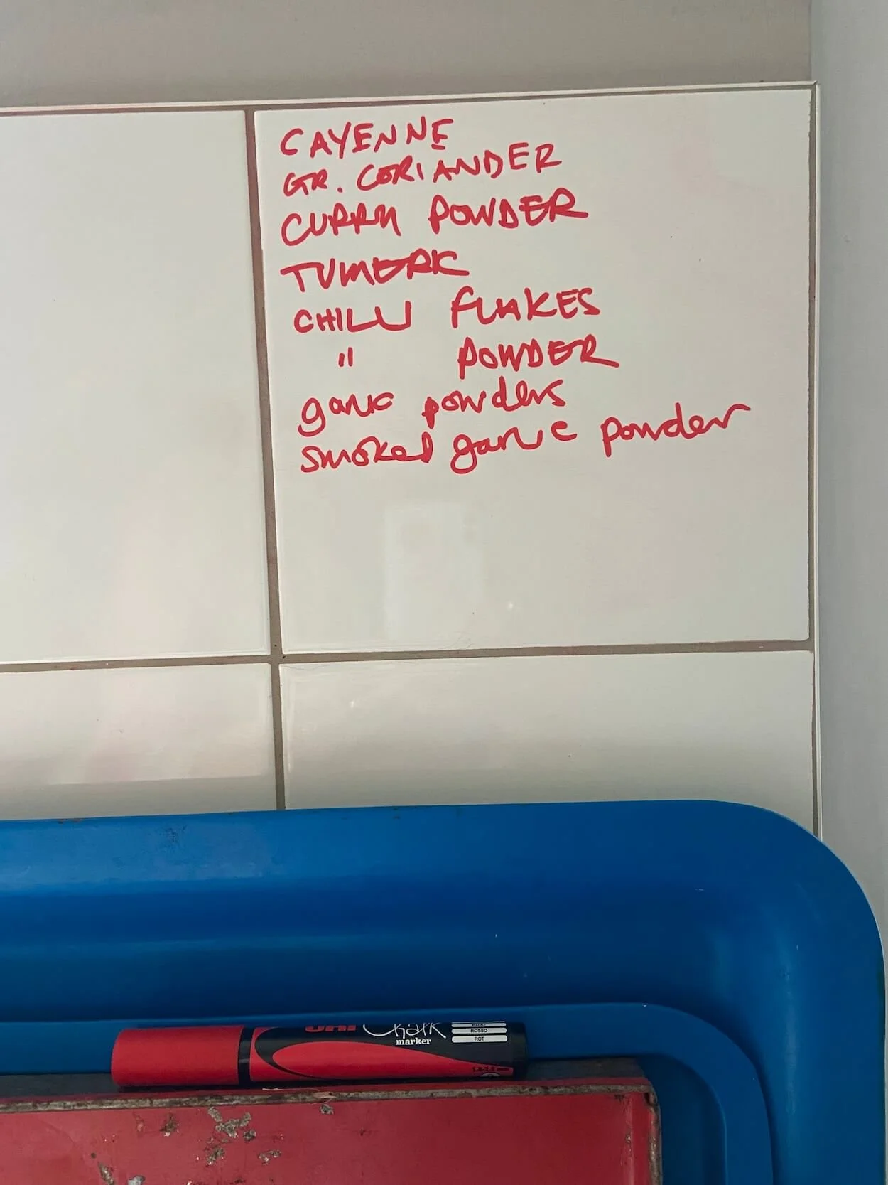 Handwritten shopping list marked directly onto kitchen tiles in Alexandra Mann's home.