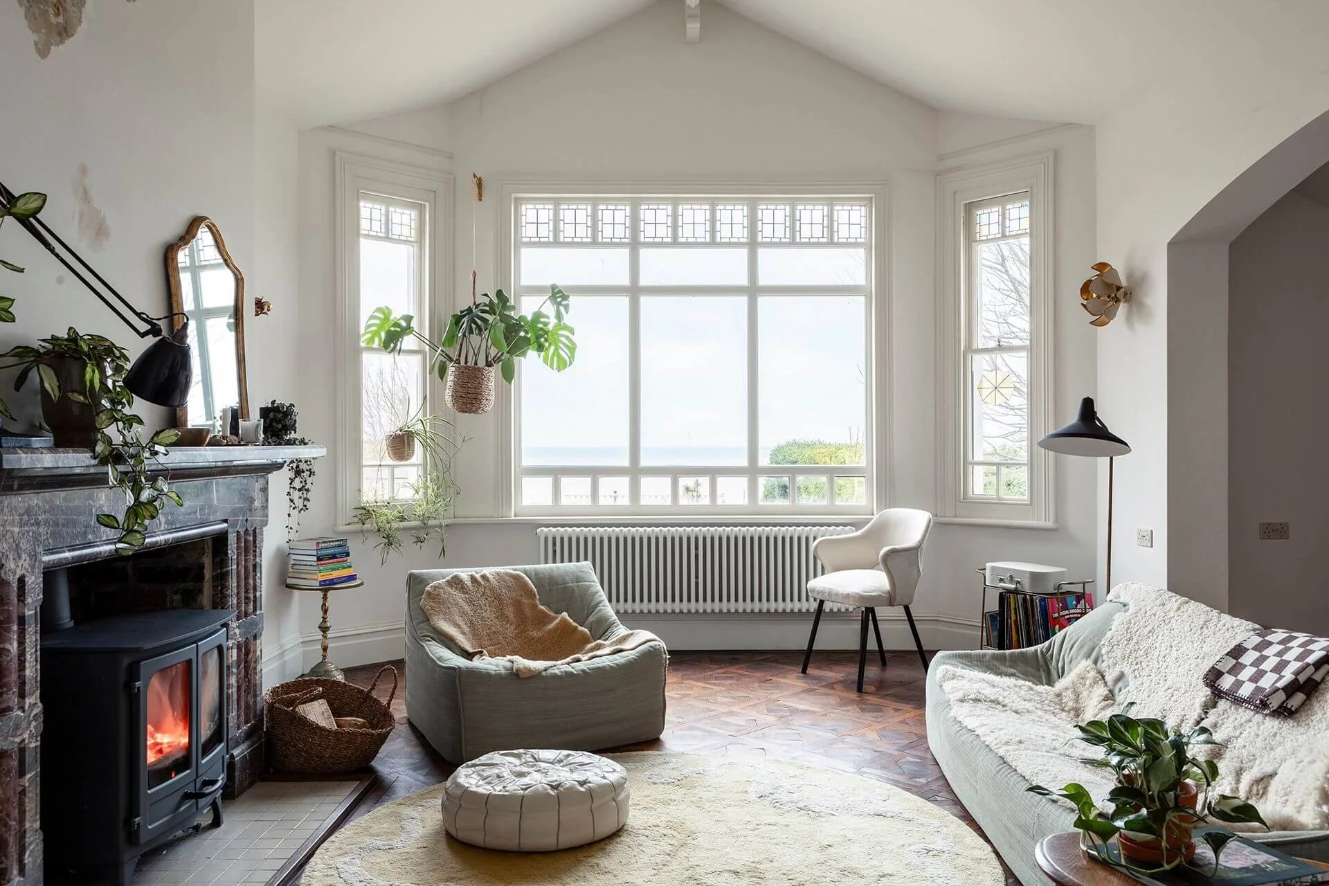The Sea Tower living room with direct sea views, a wood-burning stove in a stone fireplace, a yellow rug and a comfortable three-piece suite.