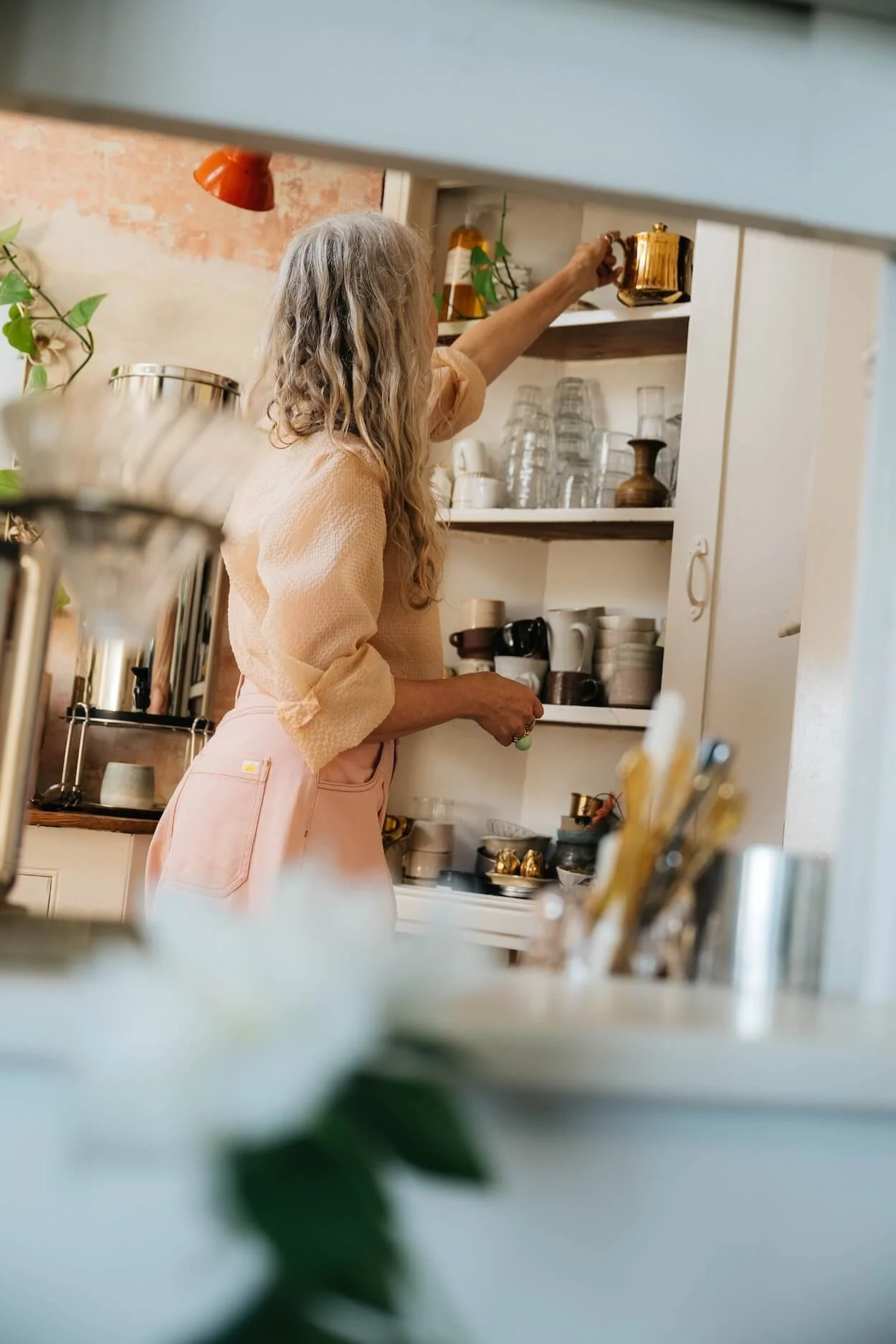 View of Emily in the butler’s pantry at Sea Tower, where a cabinet of ceramics and glassware adds to the lived-in atmosphere of the home.