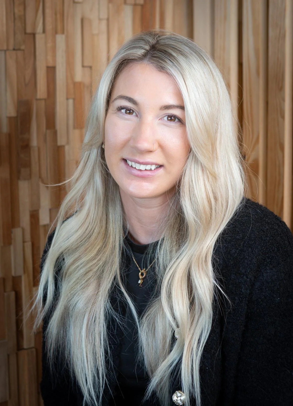 Portrait of a hair stylist smiling in the salon, showcasing their expertise and passion for hair care and styling.