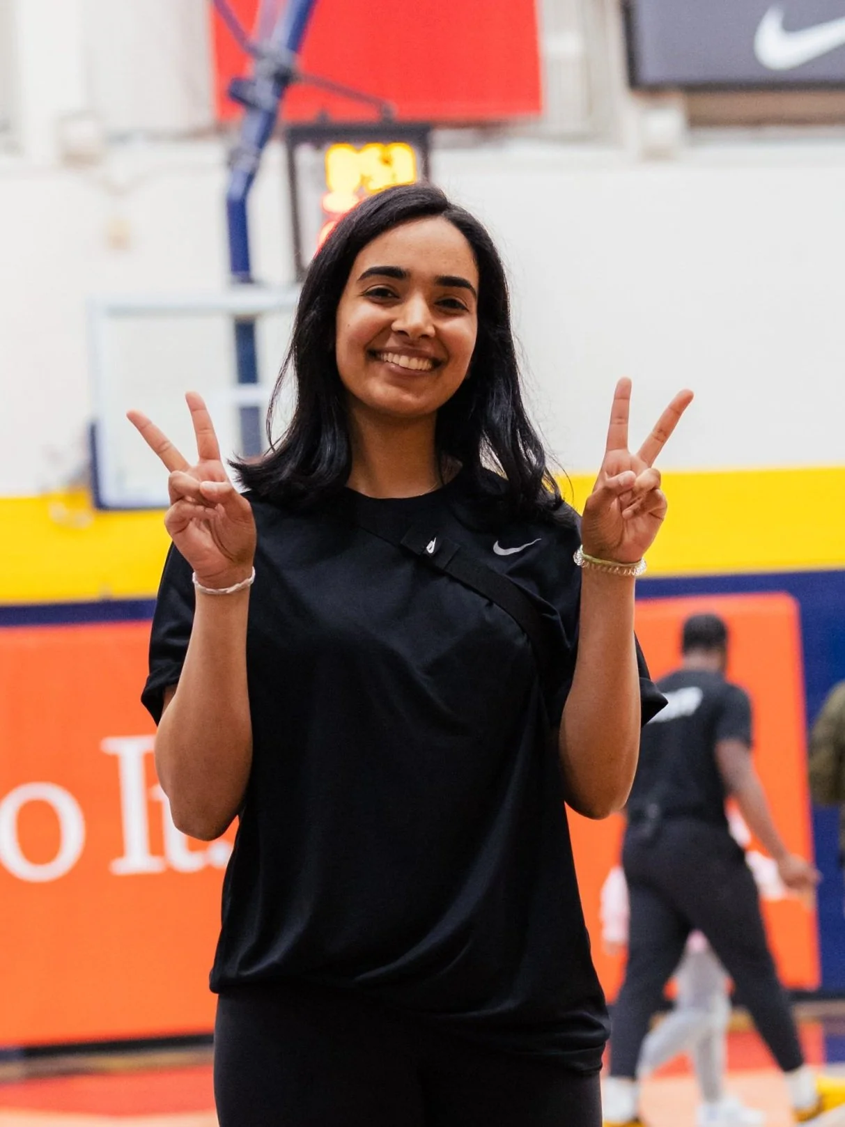 Person smiling and showing peace signs in a gymnasium