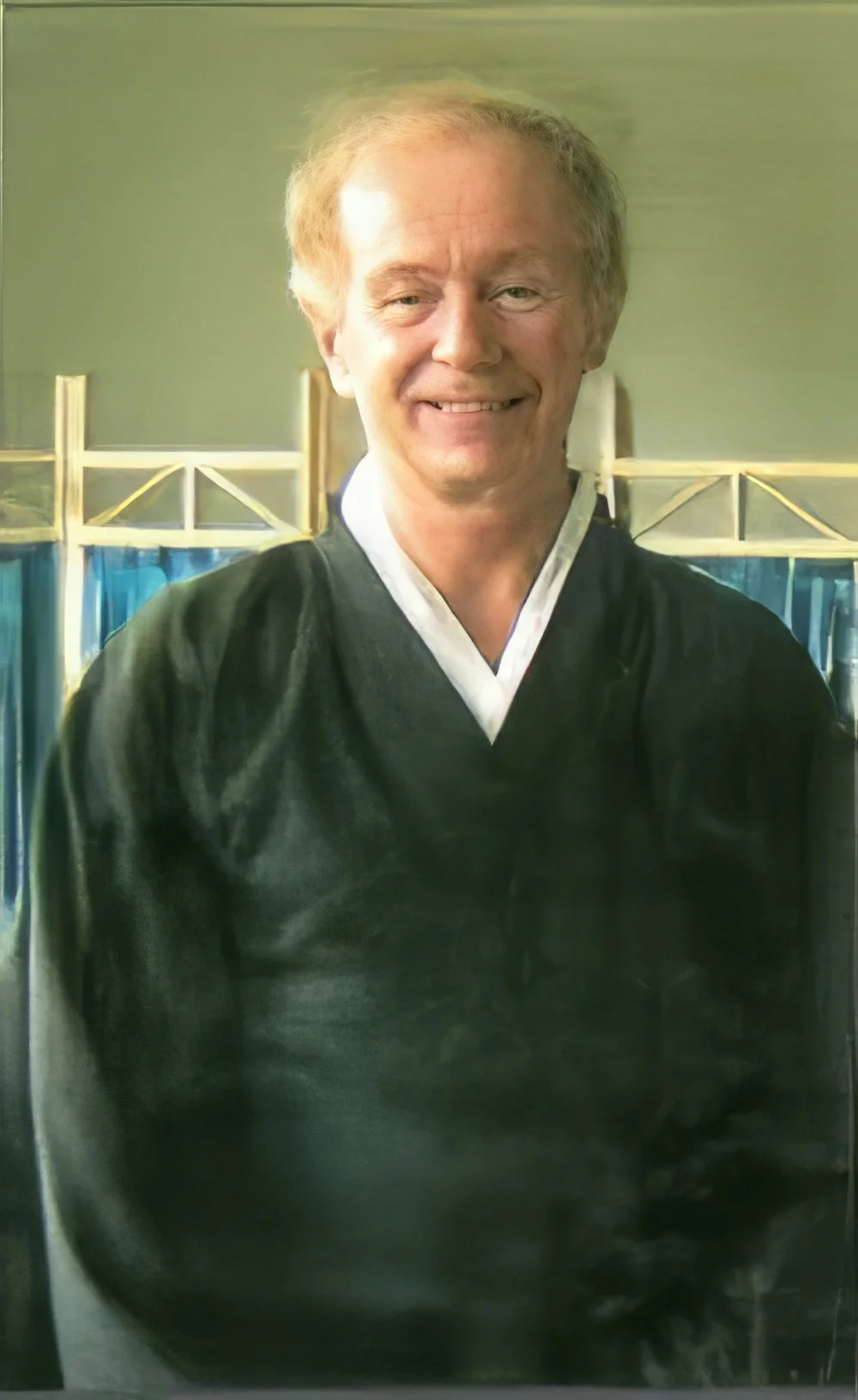 A man dressed in traditional martial arts attire smiling indoors.