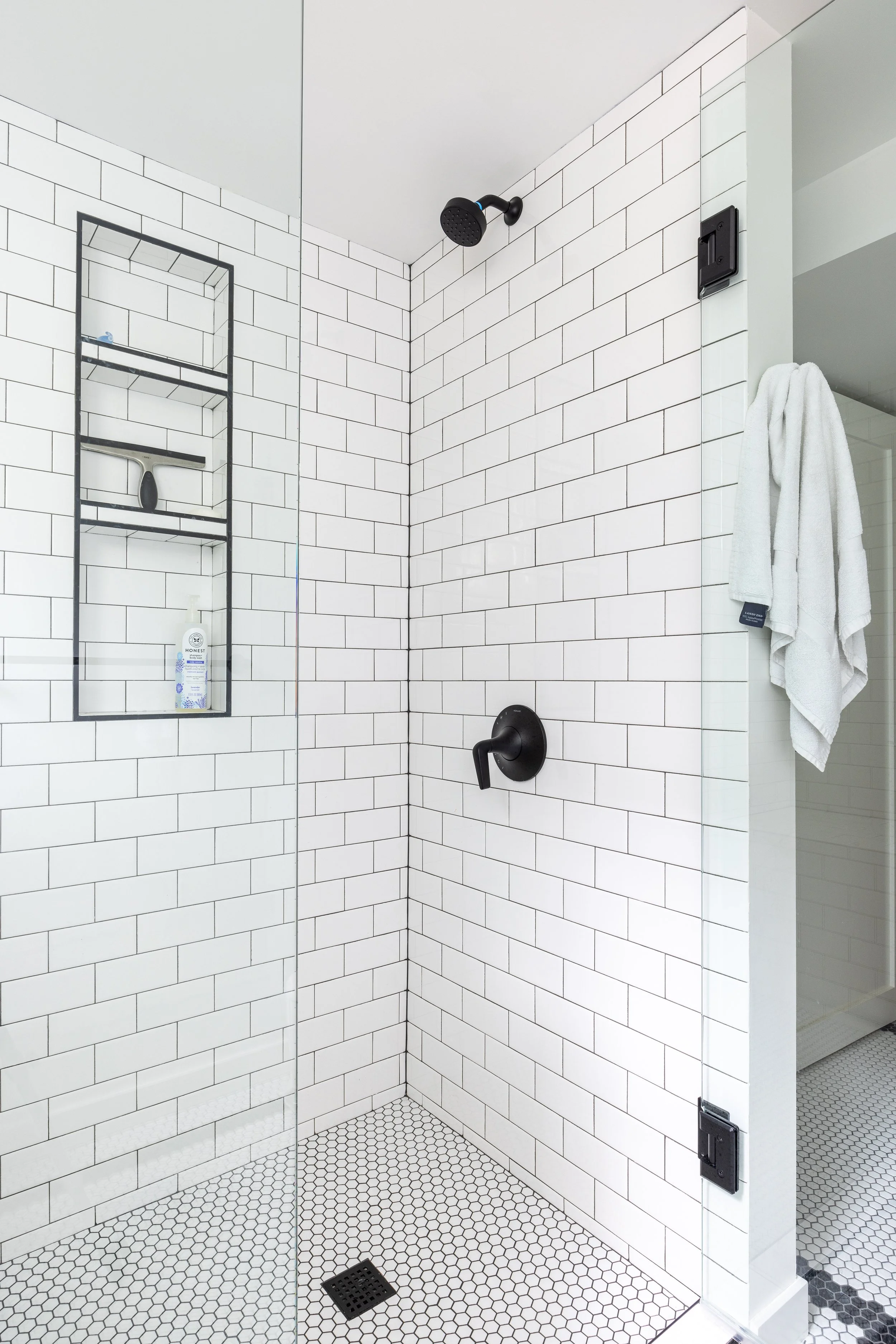Subway tile with black grout, frameless shower glass
