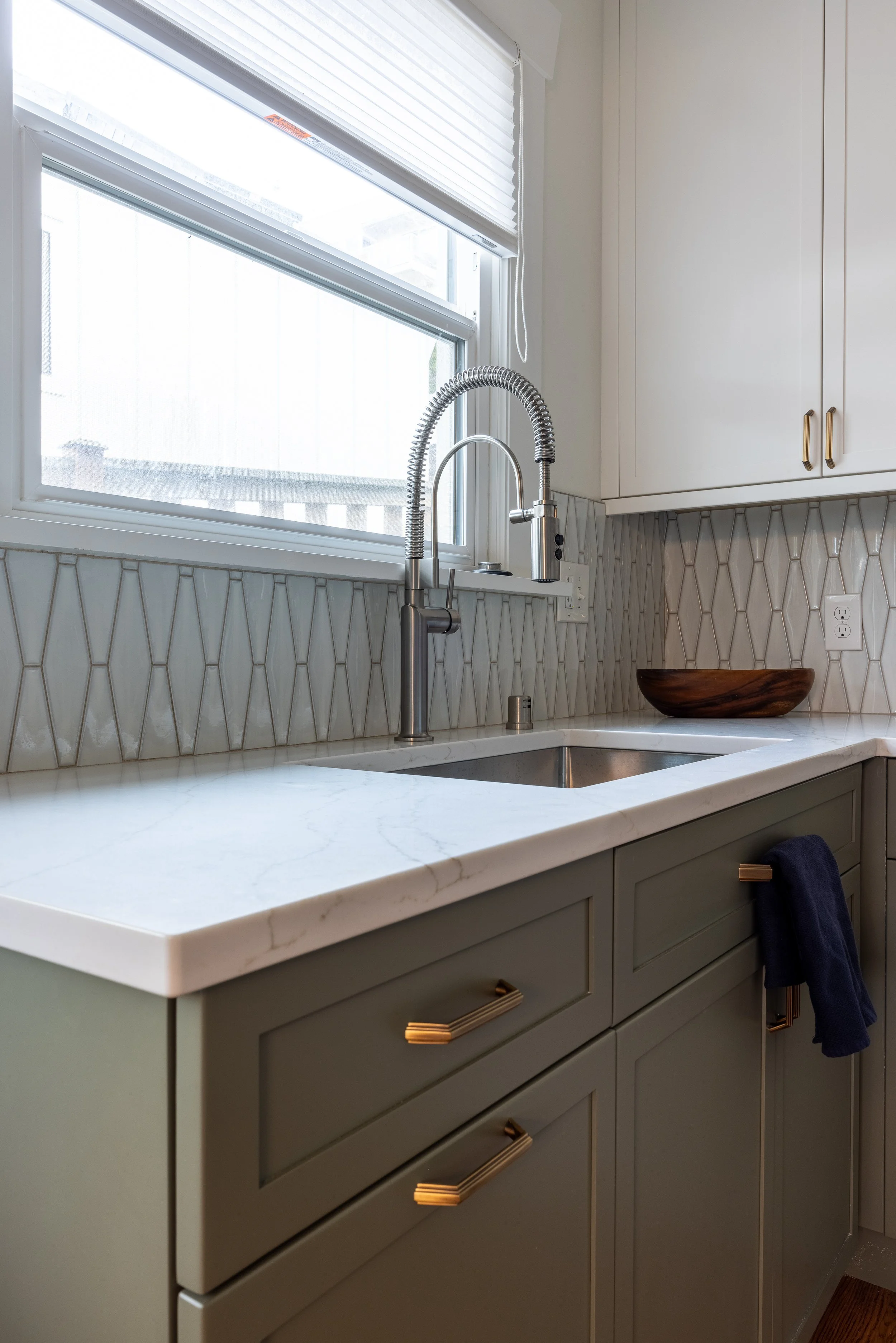 Green lower cabinets and white upper cabinets, quartz countertops, tile backsplash