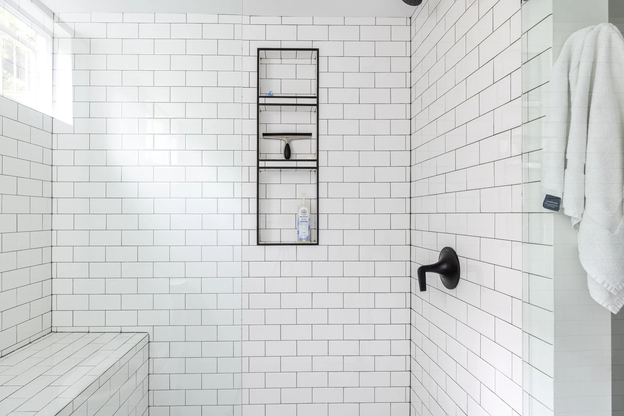 Subway tile with black grout, frameless shower glass, shower niche, shower fictures