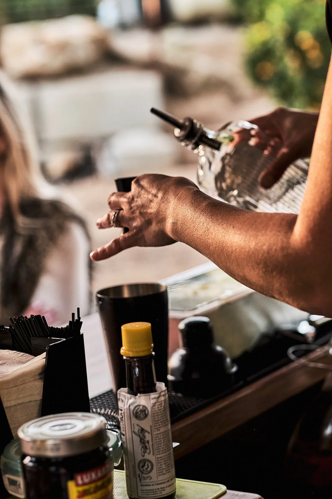 Person pouring a crafted cocktail at an outdoor event in a mobile bar