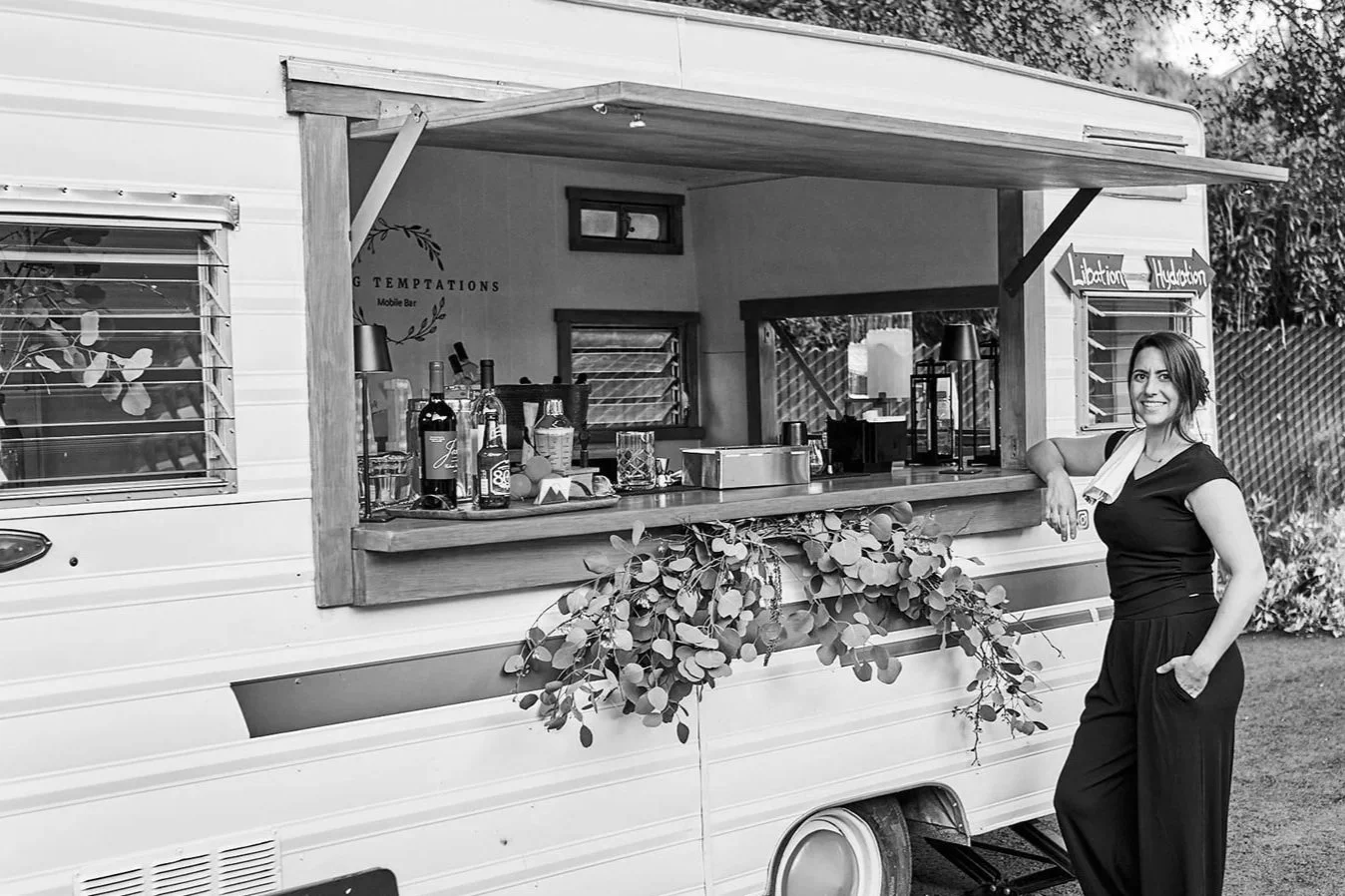 A woman standing beside a mobile bar set up in Fallbrook, CA.  outdoor event setup.