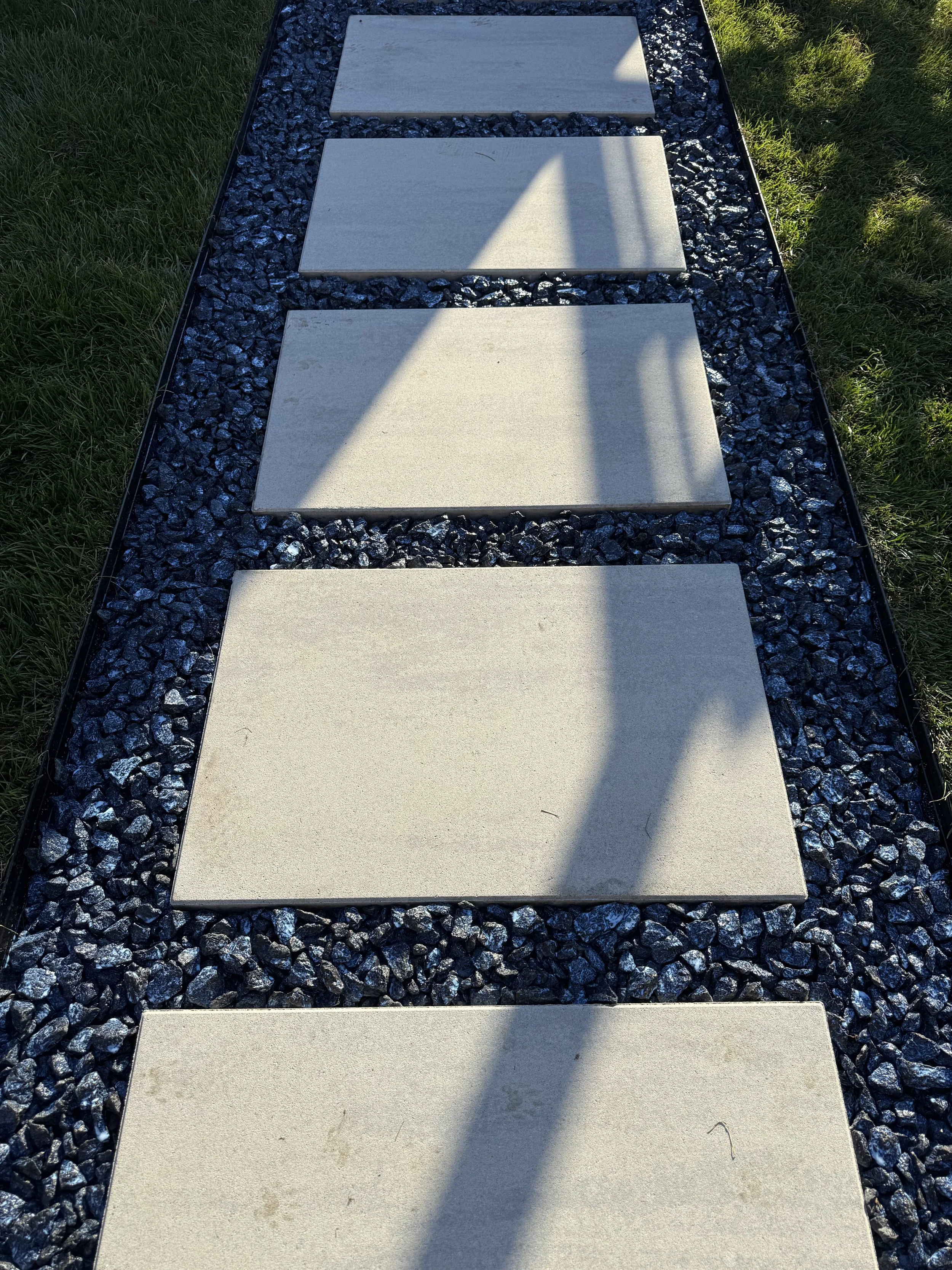 Close‑up of Blu Grande Smooth HD2 stepping stones set on compacted base with black granite infill.