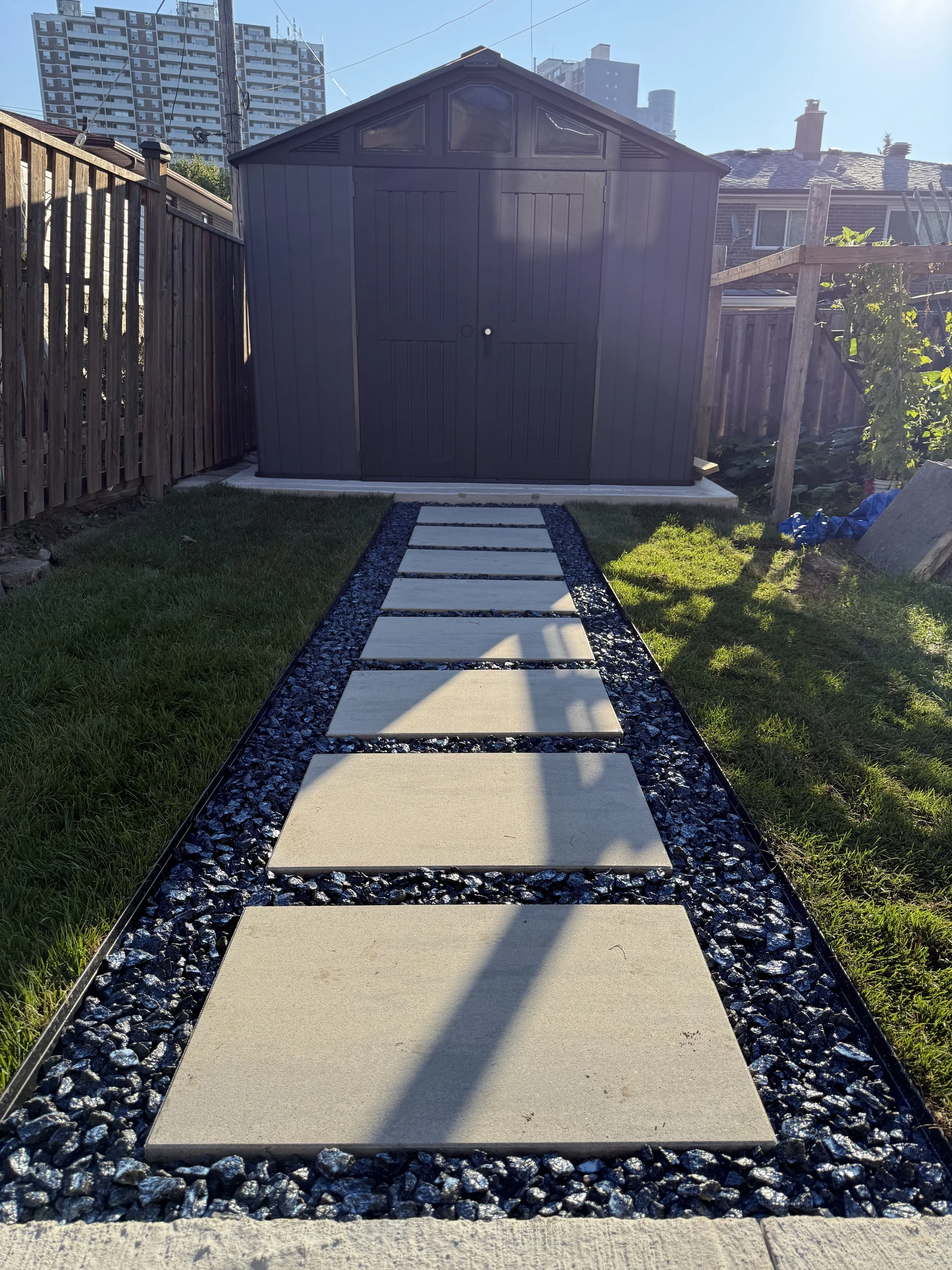 Stepping stone walkway leading to the shed using Blu Grande Smooth HD2 in Shale Grey with crushed black granite between each stone.