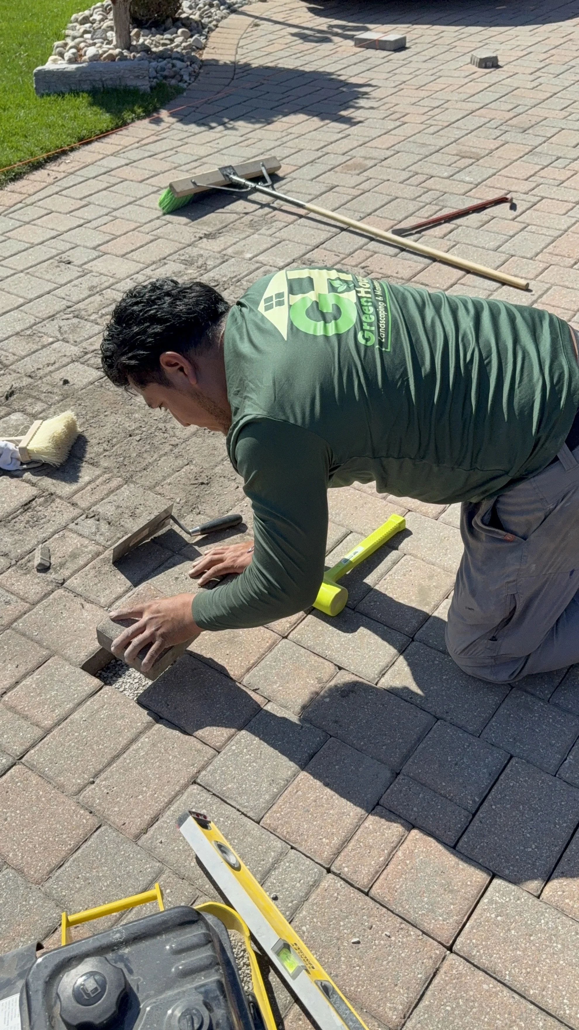Worker installing the final paving stone while re‑leveling a sunken driveway in Mississauga.