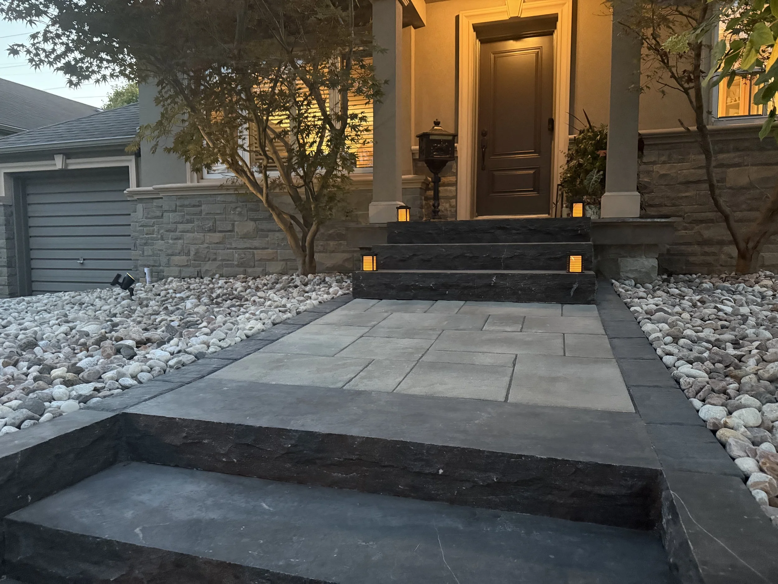 Front entrance transformation — Completed entrance rebuild with limestone steps, landing pad, and granite riverstone.