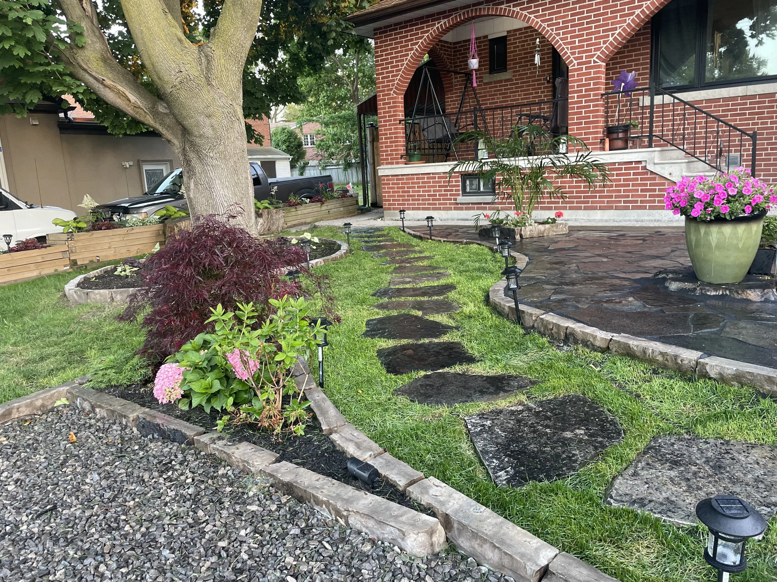 Wiarton flagstone stepping stones and a Wiarton stone pad in an Etobicoke front yard surrounded by lush, well‑designed plantings.