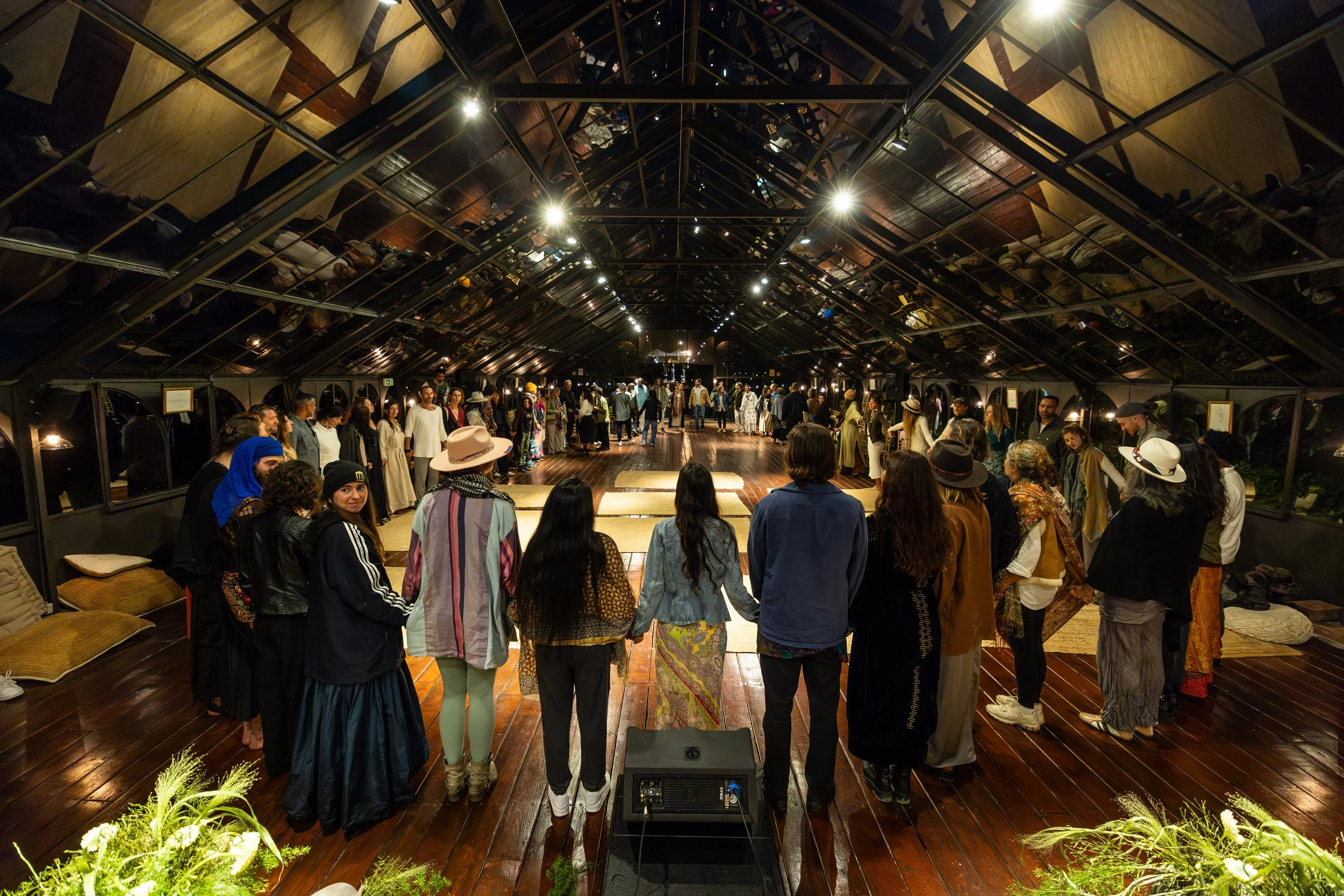 Group of people holding hands in a circle cultivating presence, and awareness at the closing ceremony of FiVth Summit 2025 in Portugal.
