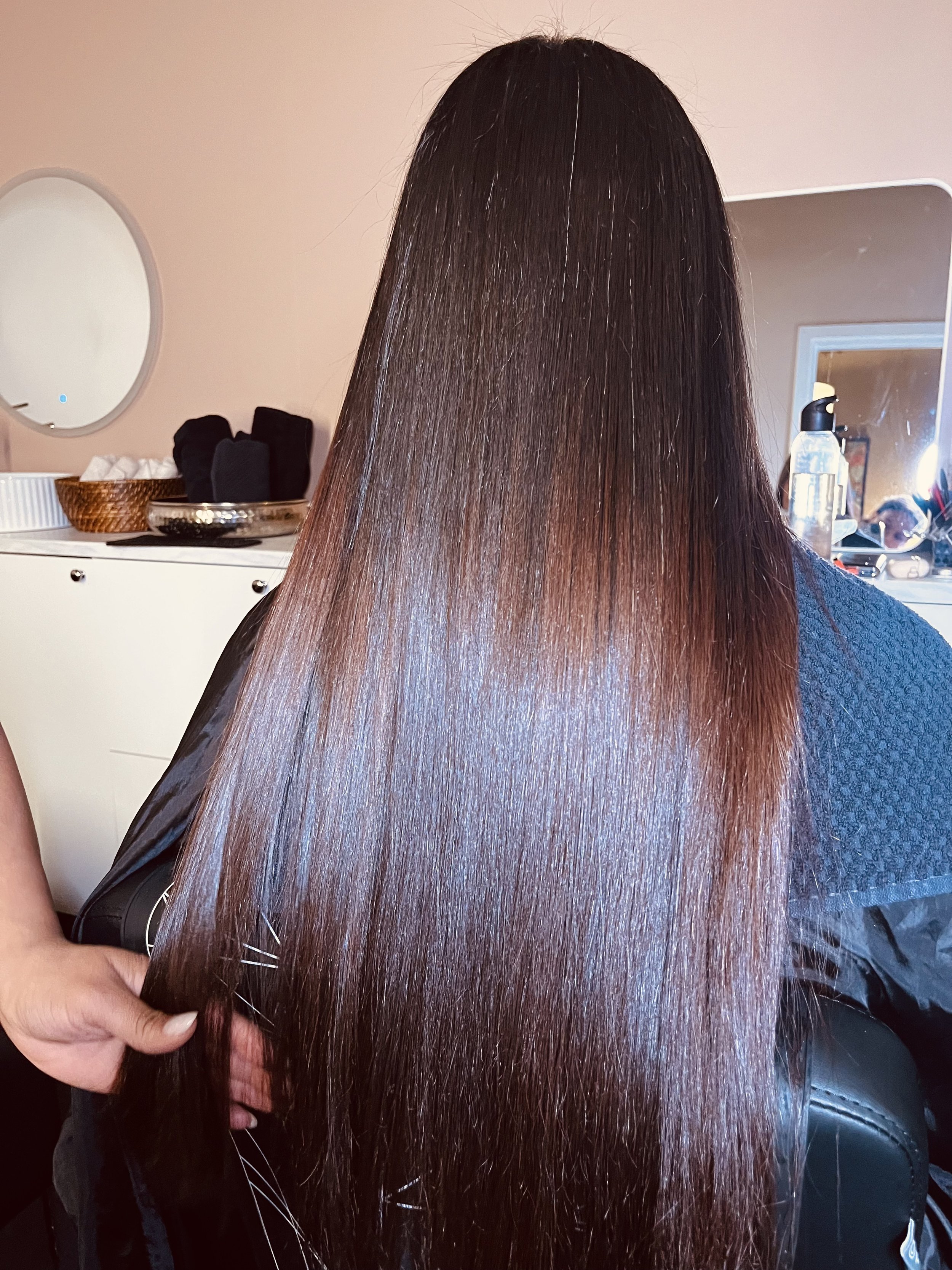 Nærbilde av en persons lange, glansfulle, brune hår som er flatbuet og rett. Keratinbehandling