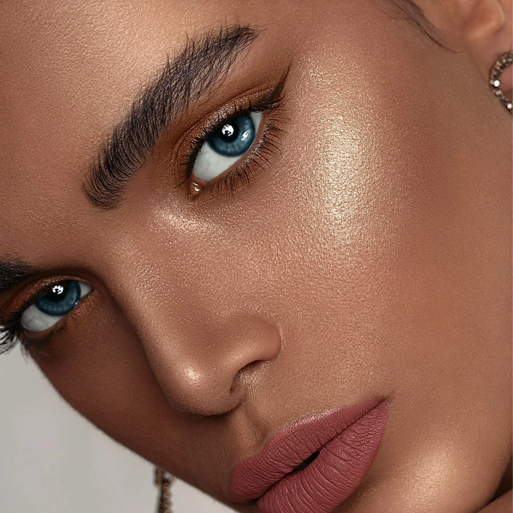 En kvinne får utført øyenbrynsskjønnhetsbehandling, med en estetiker som bruker en hvit blyant og en laser eller lysenhet.