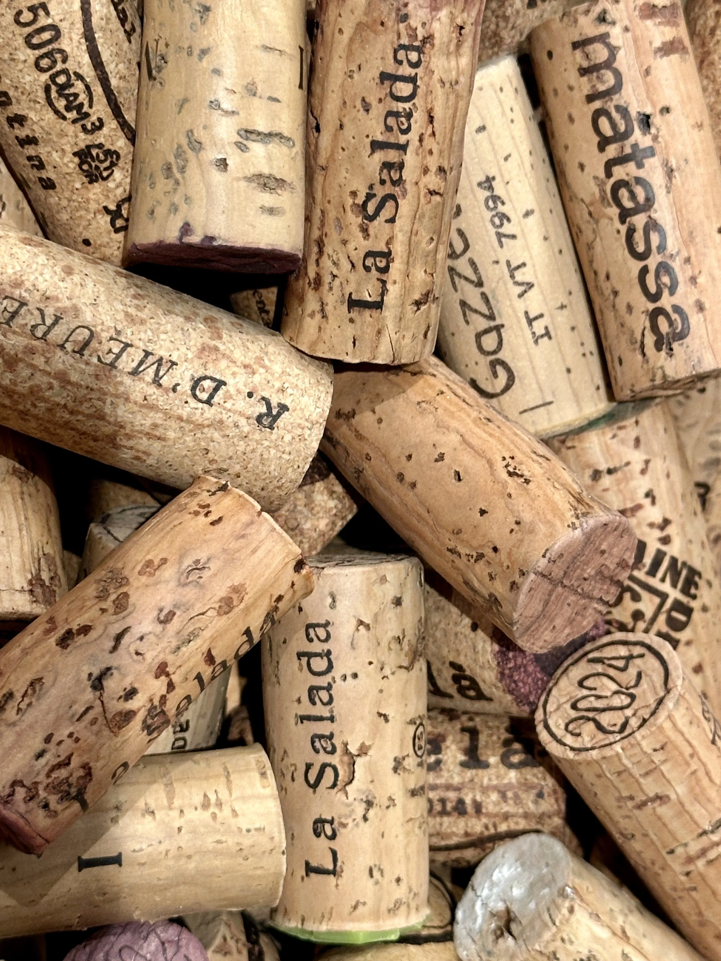 Close-up of numerous used wine corks with printed text and logos.