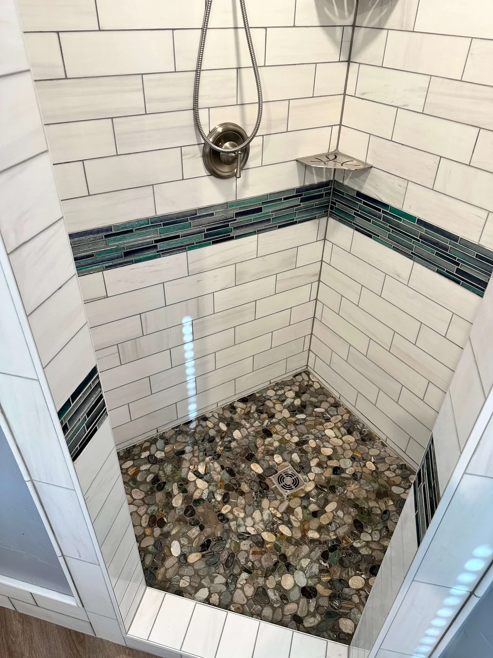 Custom subway tile shower with a pebble floor in a Logan bathroom