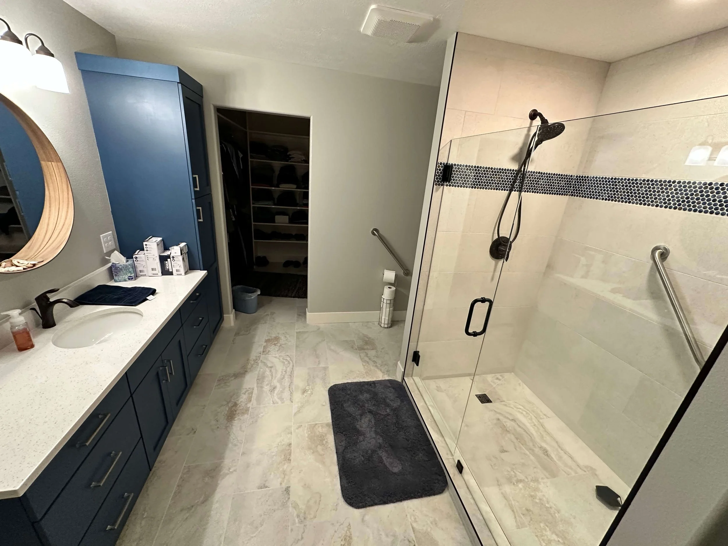 Remodeled Logan, Utah bathroom with a frameless glass shower, blue vanity, and white countertop by ONYX Bros
