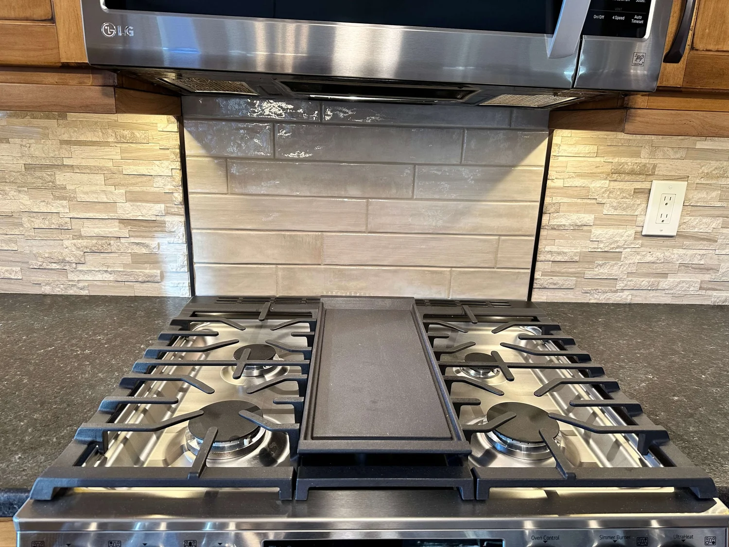 Stone-look linear tile backsplash behind a gas range in a Logan, Utah kitchen
