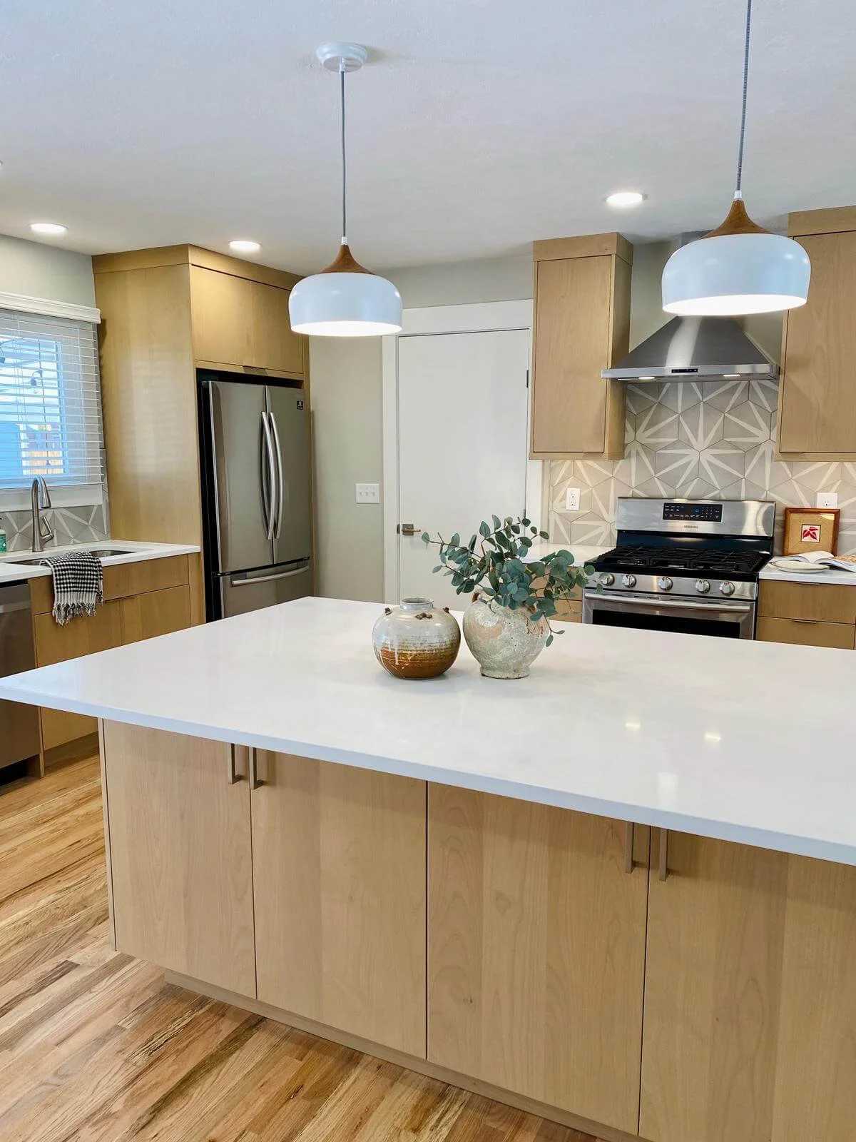 Modern kitchen remodel near Logan, Utah by ONYX Bros with a waterfall island and patterned tile backsplash