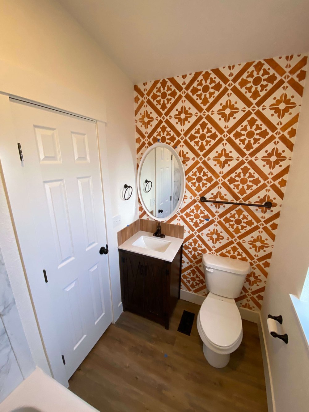 Small Logan bathroom refreshed with a patterned orange tile accent wall and dark wood vanity