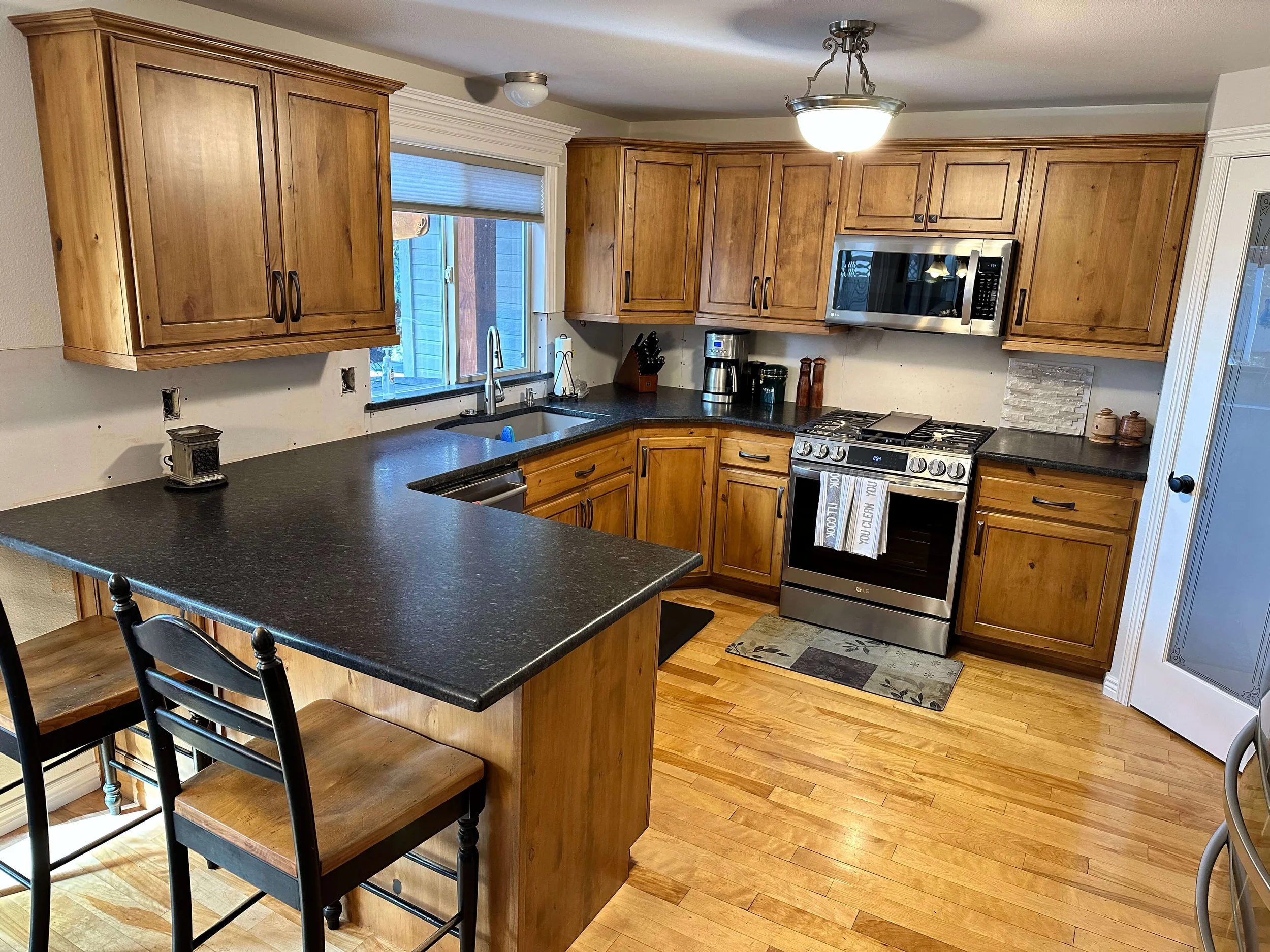 Kitchen remodel in Logan, Utah by ONYX Bros, wood cabinets and a black-topped island with seating