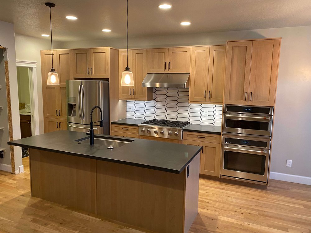 Kitchen remodel in Logan, Utah with wood cabinets, a dark island countertop, and pendant lights