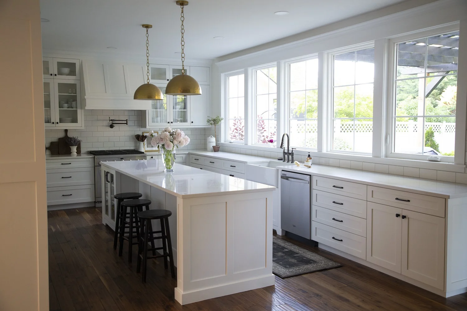 Bright white kitchen remodel with a wall of windows and an island by ONYX Bros