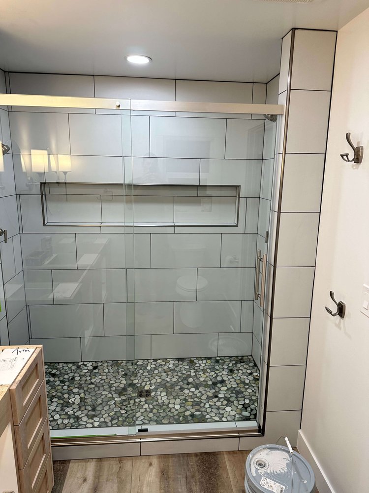 Finished walk-in tile shower with a glass enclosure, long niche, and pebble floor in Logan, Utah