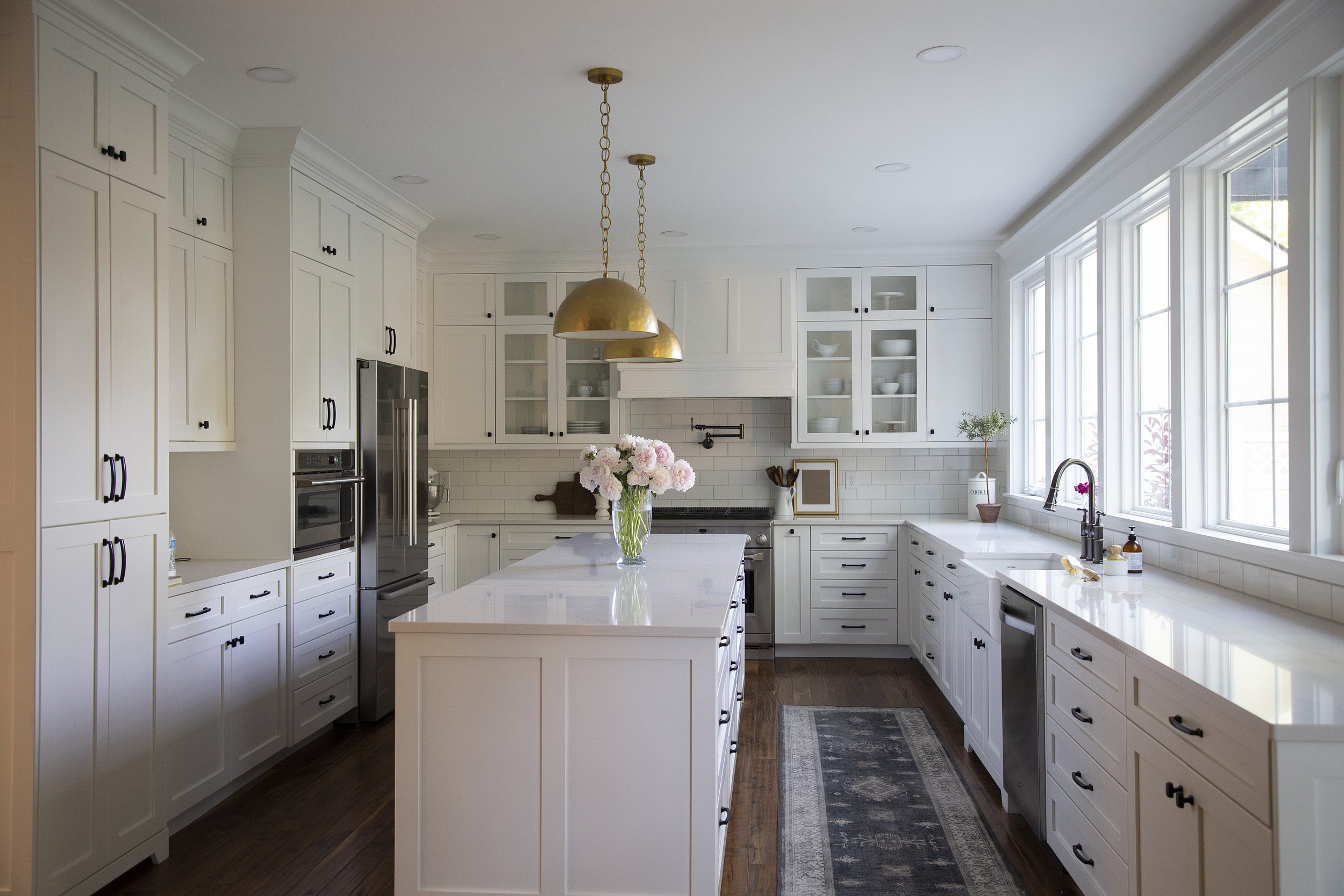 Finished white kitchen remodel in Logan, Utah by ONYX Bros, large island with quartz counters and gold pendant lighting