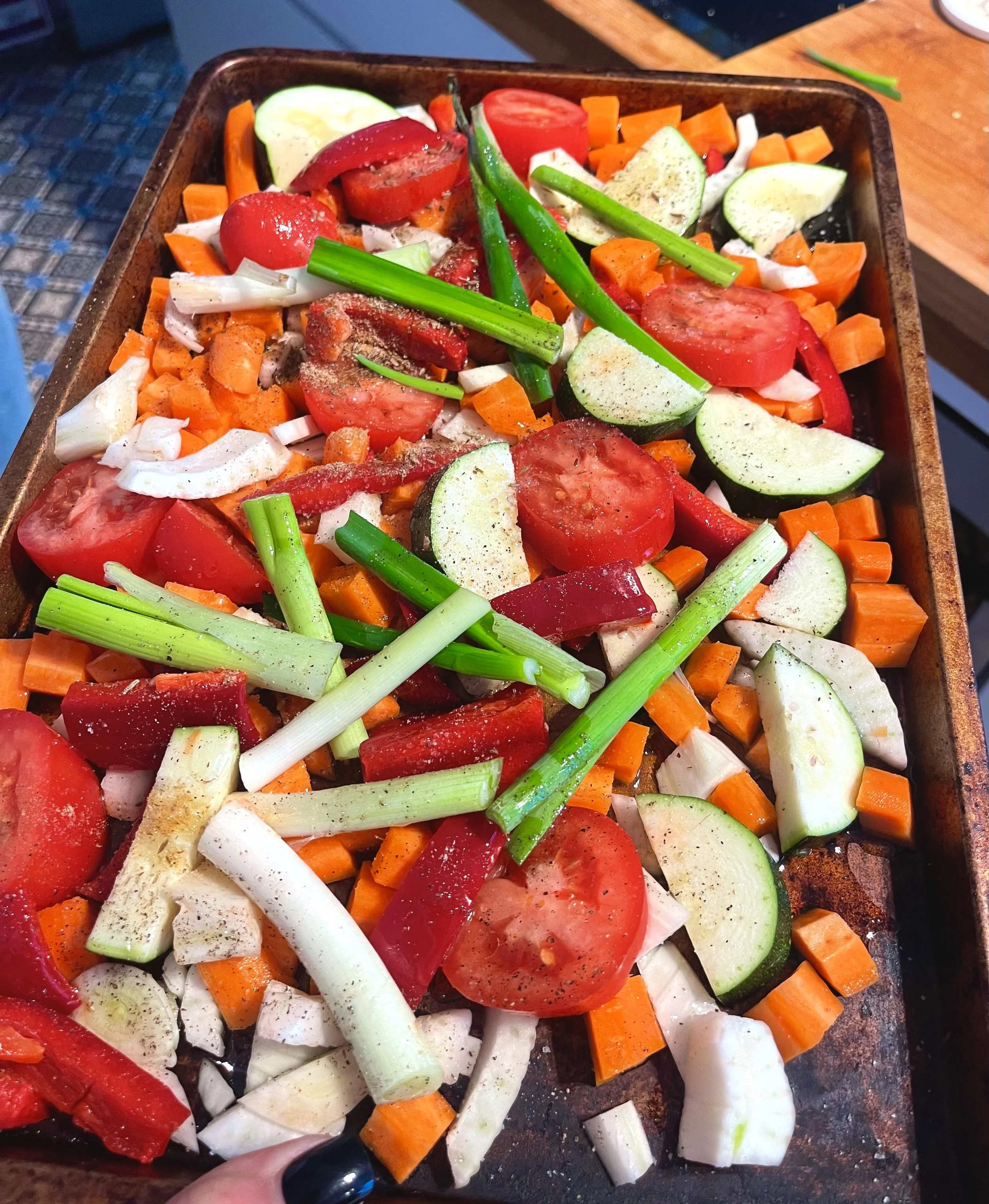 Gepakte groenten klaar om geroosterd te worden, inclusief courgette, tomaat, wortel, groene ui en paprika.