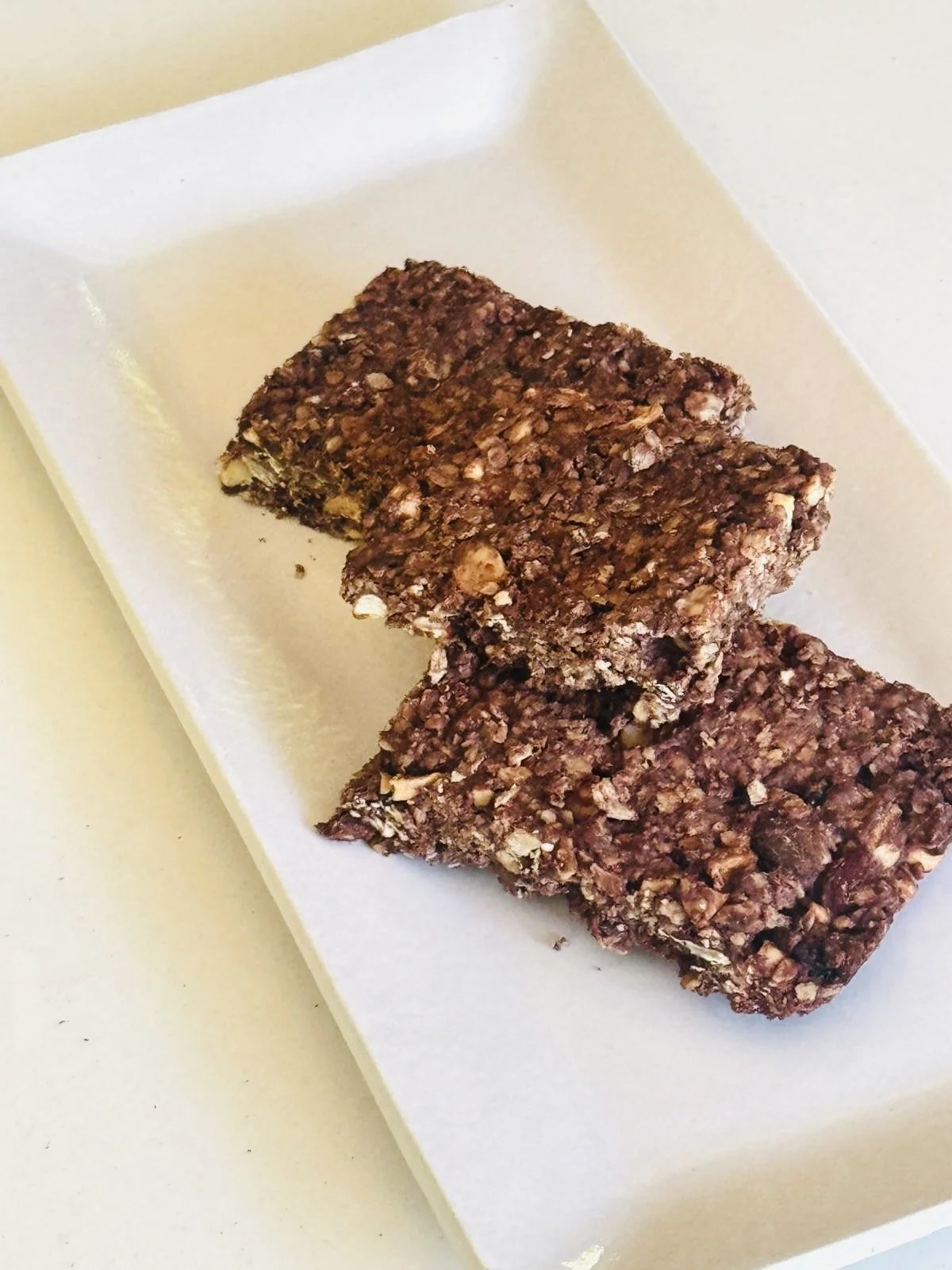 Twee repen mueslireep op een wit bord.