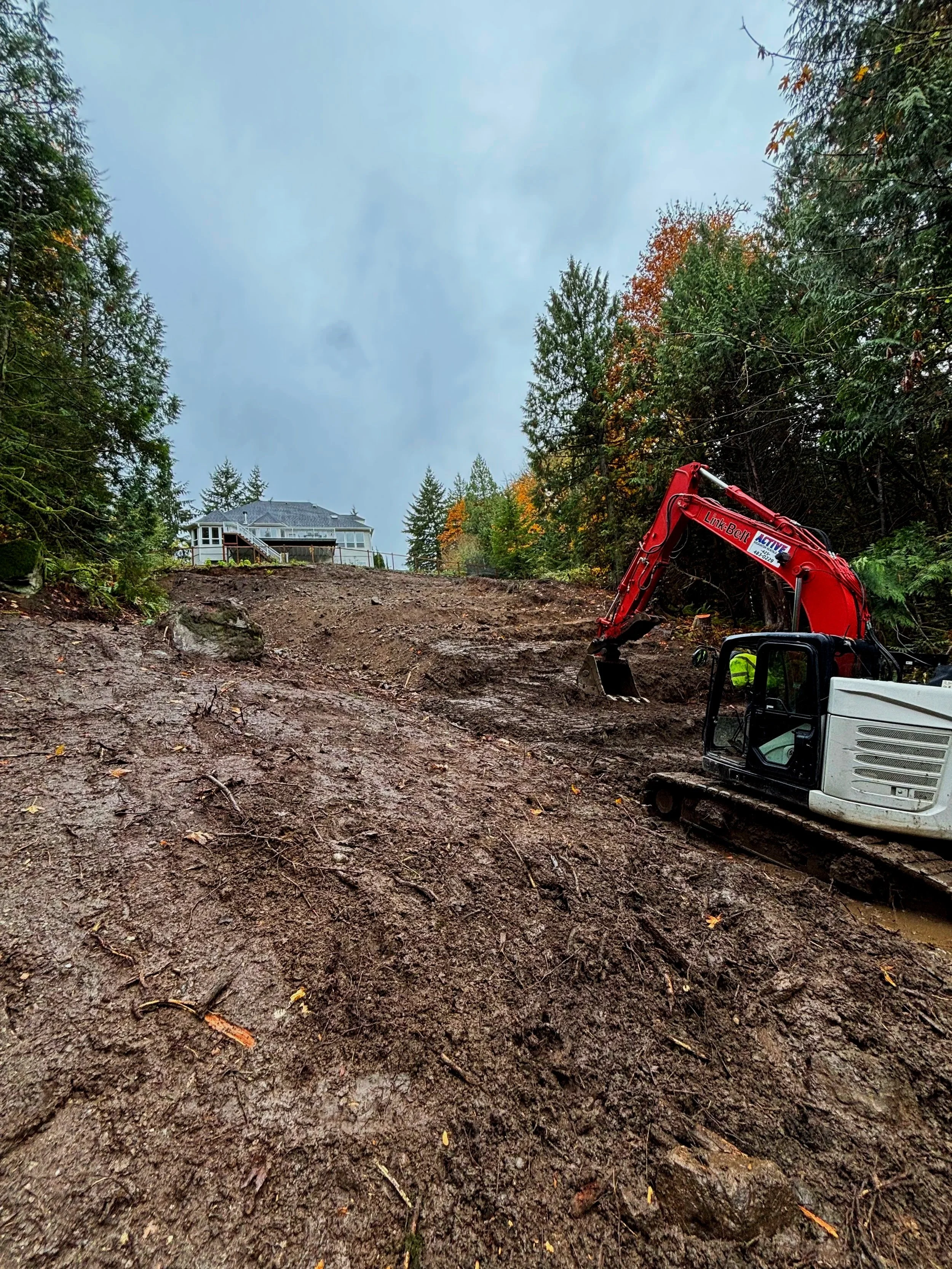 Small excavator working on a hillside property for a Snohomish Landscaping project.
