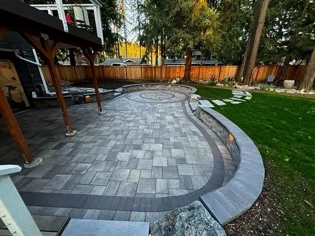 Sunken paver patio with retaining walls surrounded by lawn and paver steps.