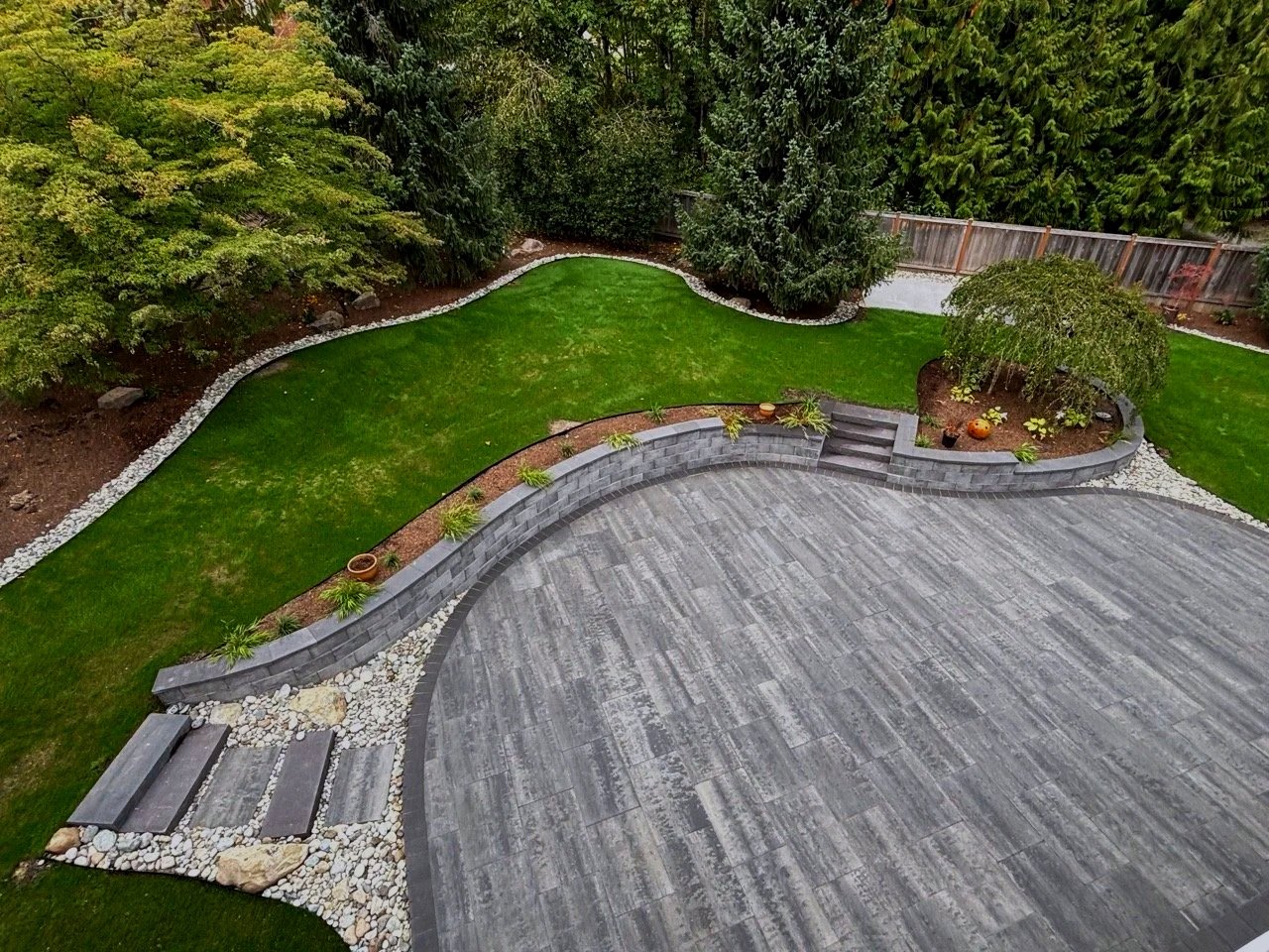 Huge arched paver patio design, steps, lawn and plants as part Monroe landscape company consturction.