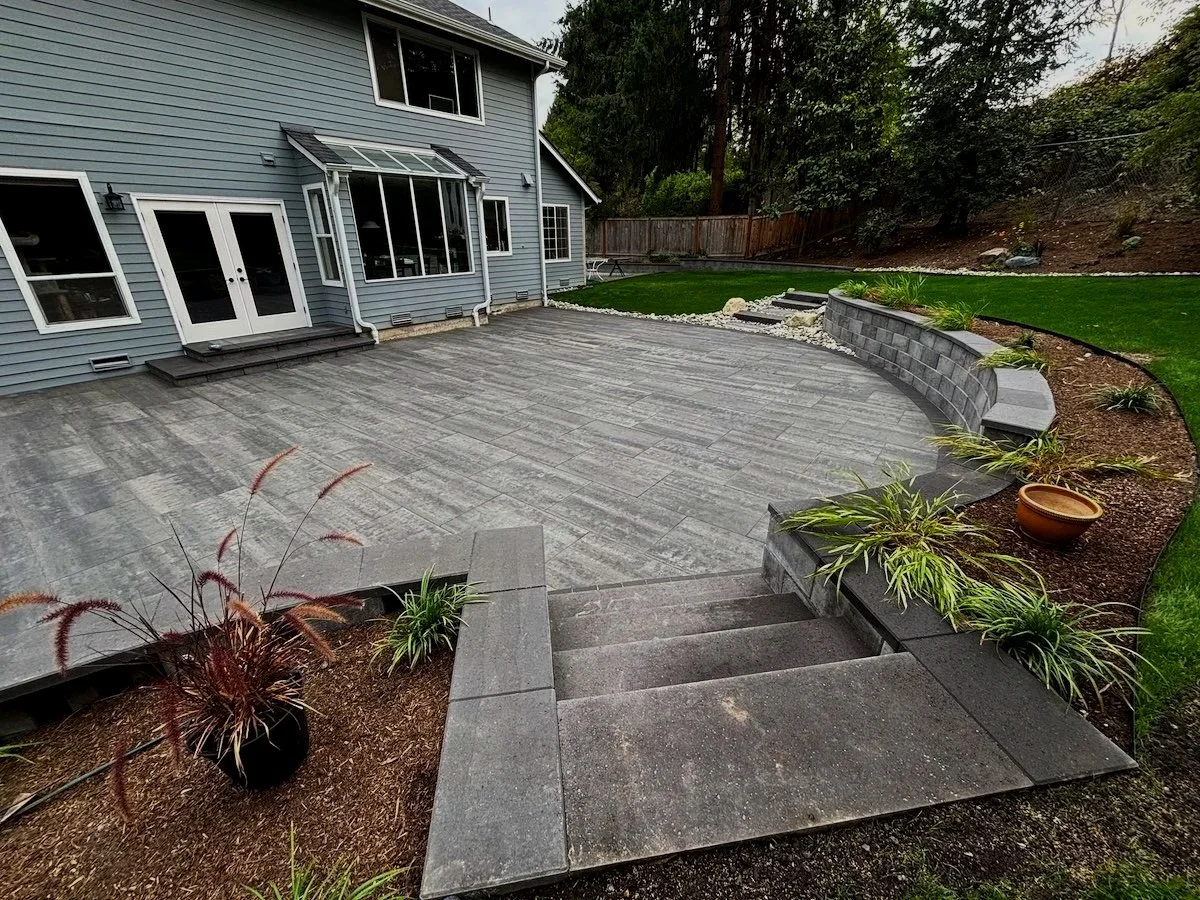 Beautiful retaining wall backyard patio with plants design and lawn in Redmond Washington.