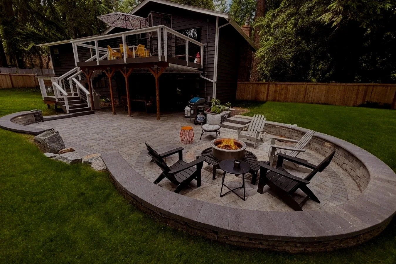 Retaining wall custom paver patio with a chairs as part of backyard design in Monroe Washington.