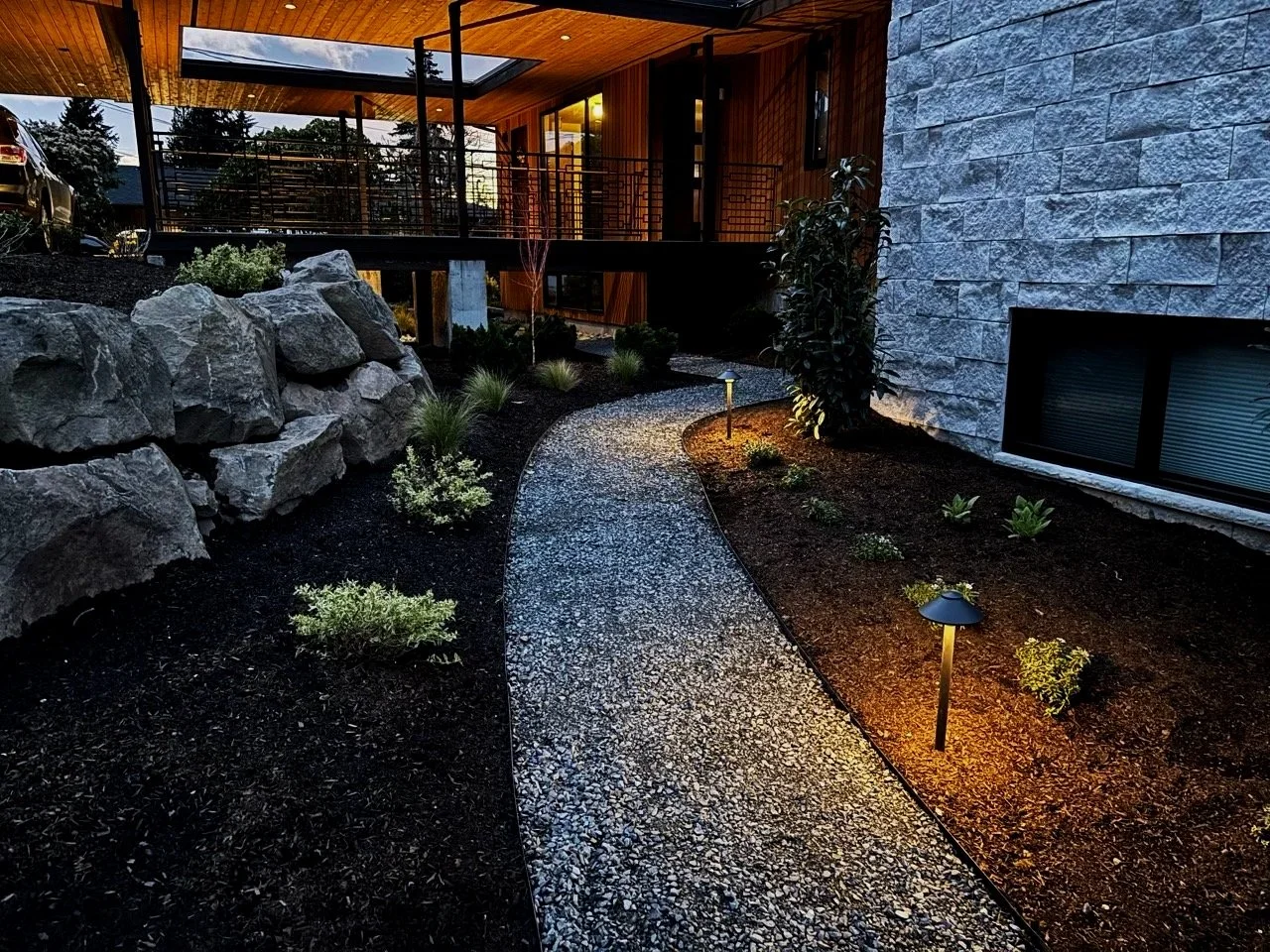 Gravel pathway to a house with plants and landscape lights created by Snohomish Landscape Designer.