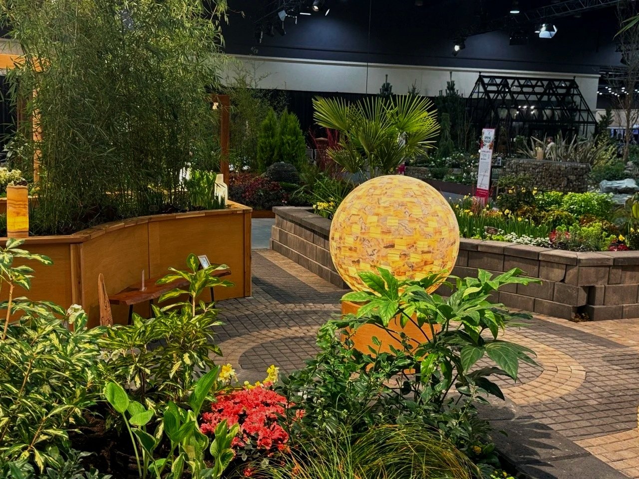 Round landscaping light fixture and spiral paver design with trees and plants.