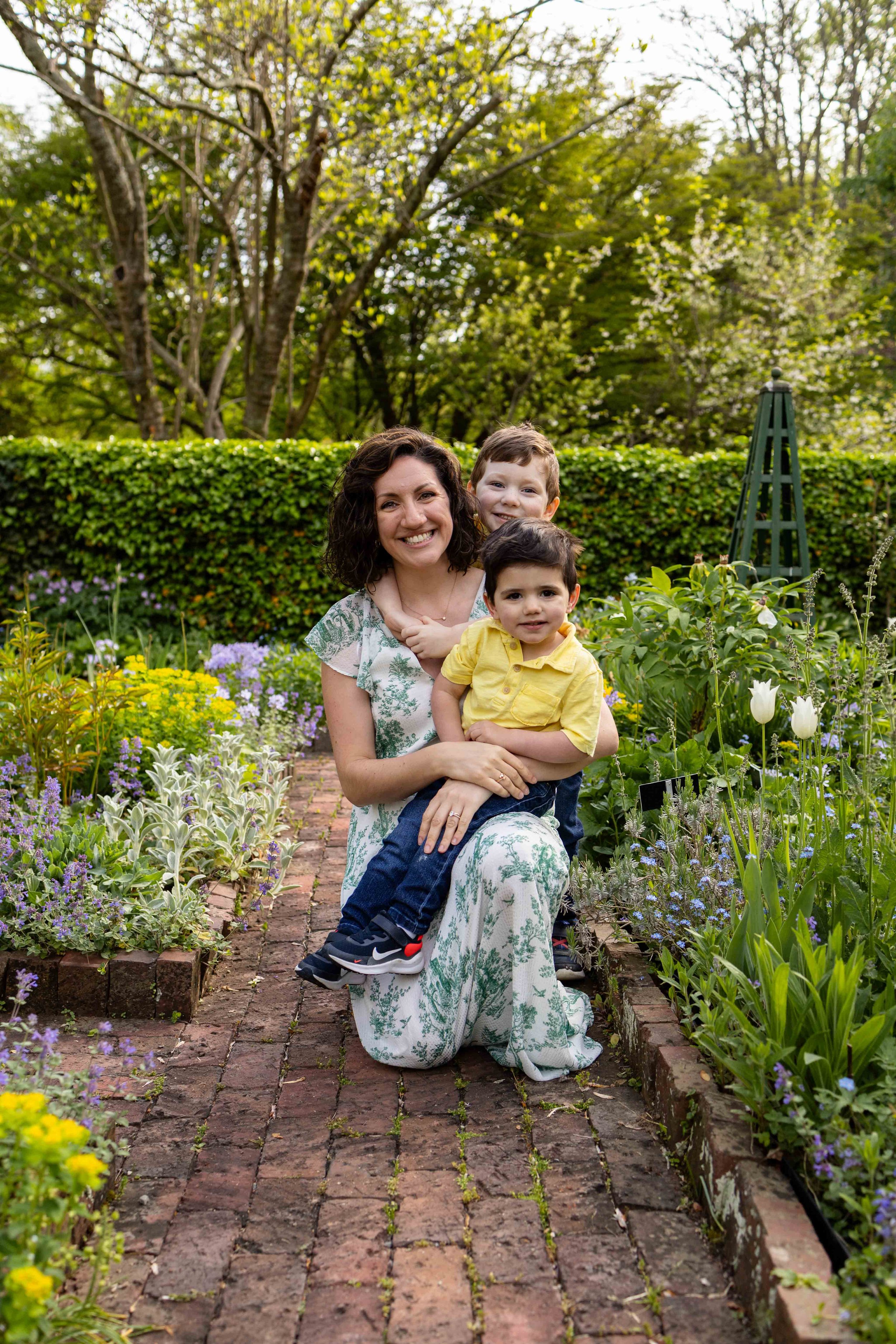 Mom hugs her two children while in a perennial garden in spring - family photo taken by Jennifer Fulton Photography in Basking Ridge, NJ