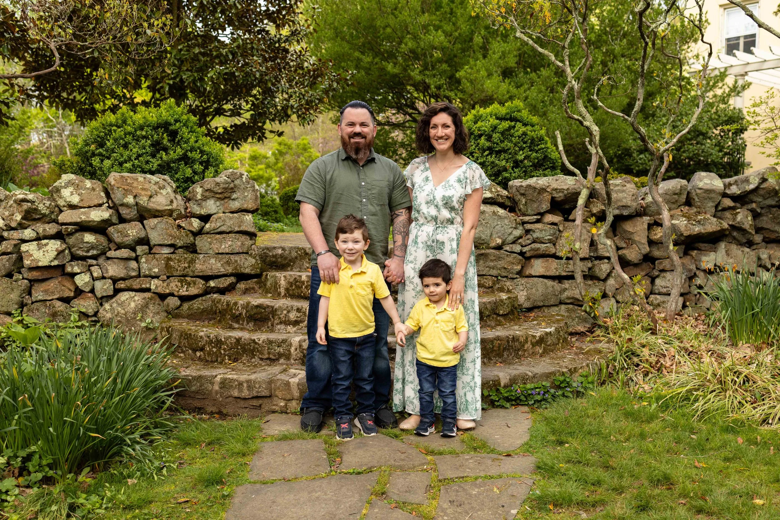 A family with two young children stand in a garden - family photo taken by Jennifer Fulton Photography in Bridgewater, NJ
