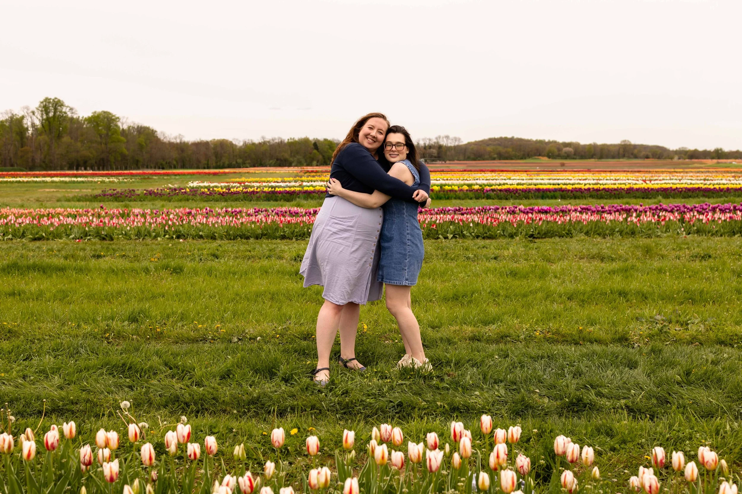 Two friends embrace while standing in a tulip field - best friends portrait taken by Jennifer Fulton Photography in North Jersey